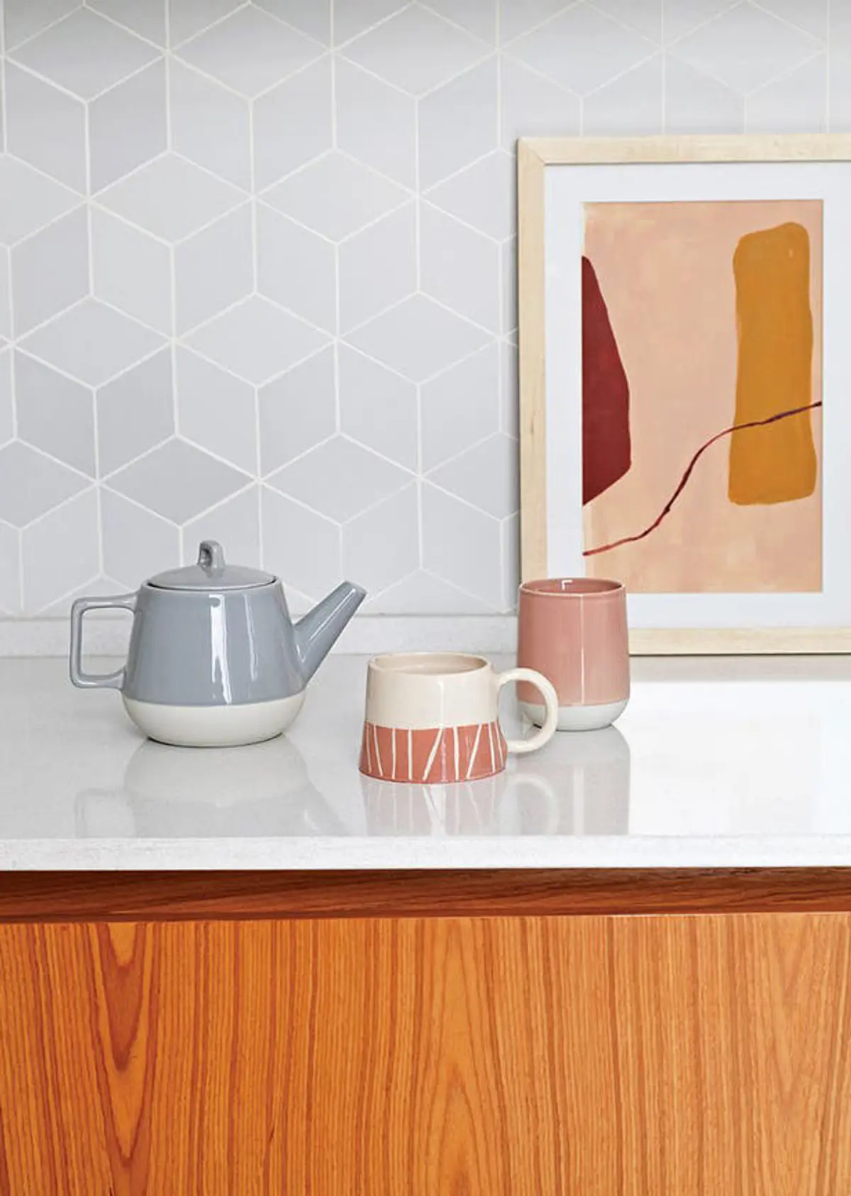 Teteras y tazas en mesada de cocina con pared de azulejos geométricos — proyecto Obra HNDRS, por Ideï Arquitectura, en CABA