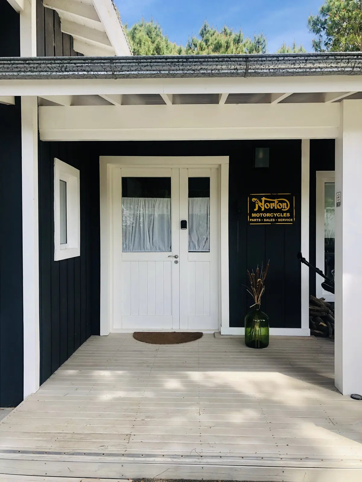 Fachada de casa moderna com varanda de madeira e placa Norton — projeto Costa Esmeralda, por Greschek Obras, em Costa Esmeralda