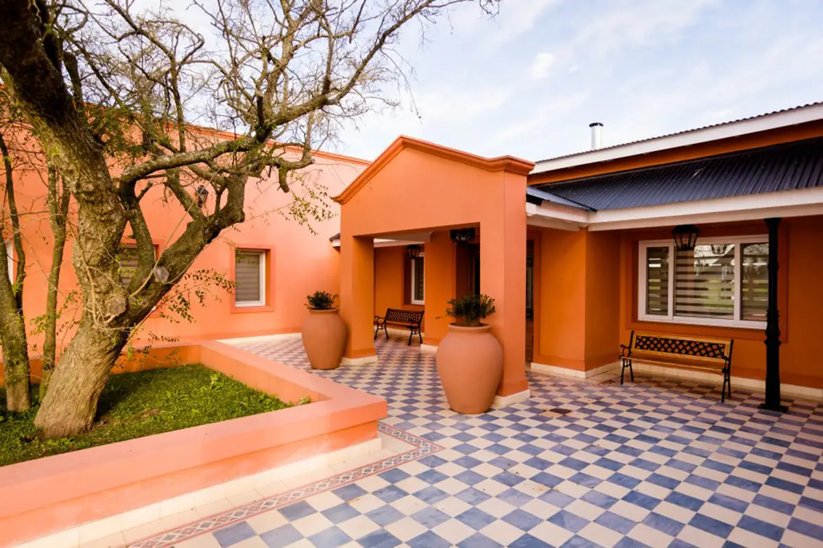 Fachada de casa mediterrânea com piso quadriculado e detalhes em terracota — projeto La casa del árbol, por Estudio Fernandez Long & asoc., em Canning