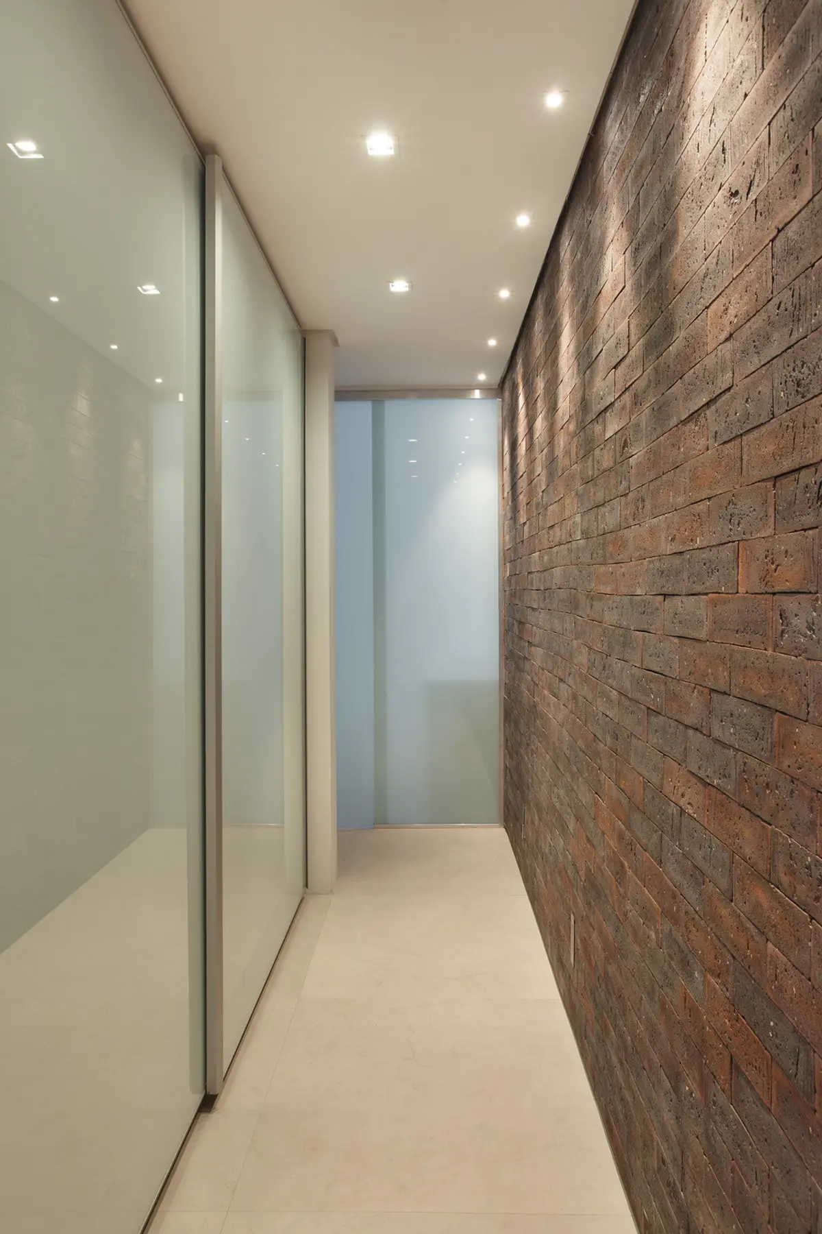 Pasillo minimalista con pared de ladrillo visto y vidrio esmerilado — proyecto VF House, por Studio Ro-ca