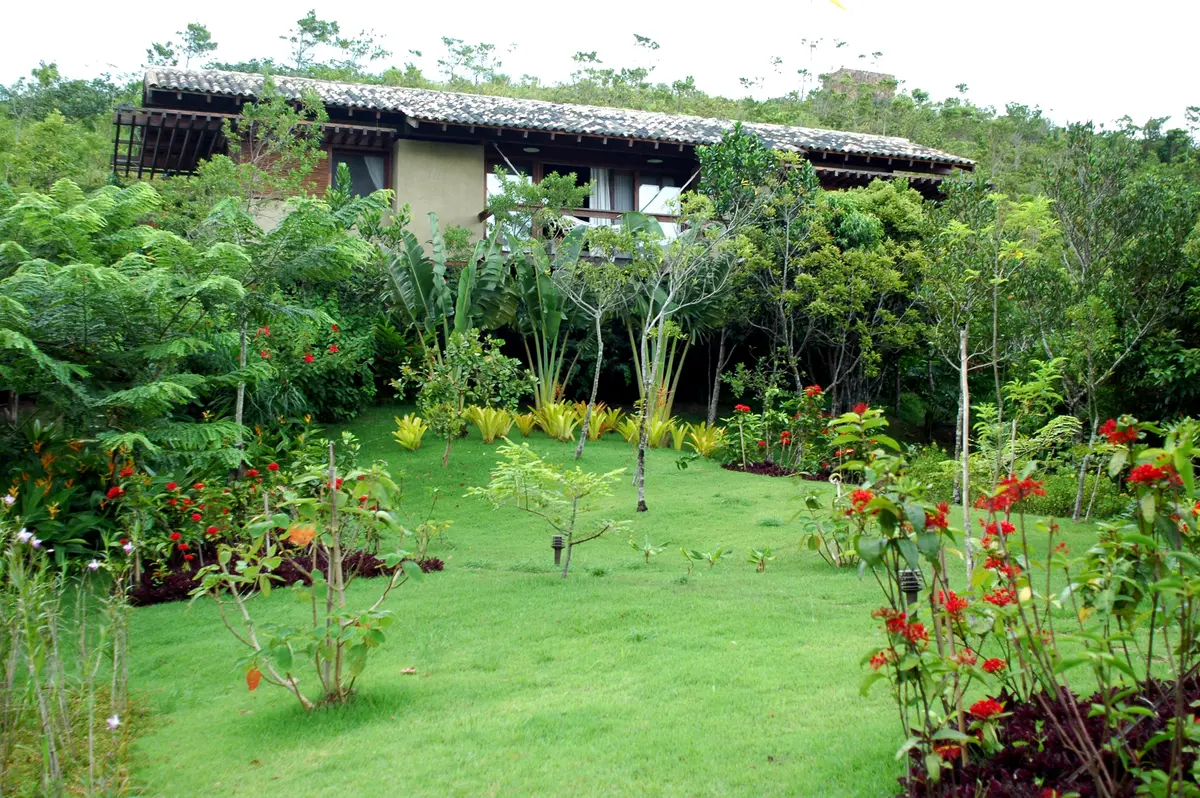Casa de campo con jardín verde y plantas ornamentales en patio trasero — proyecto Fazenda Indaiauba, por Gil Fialho