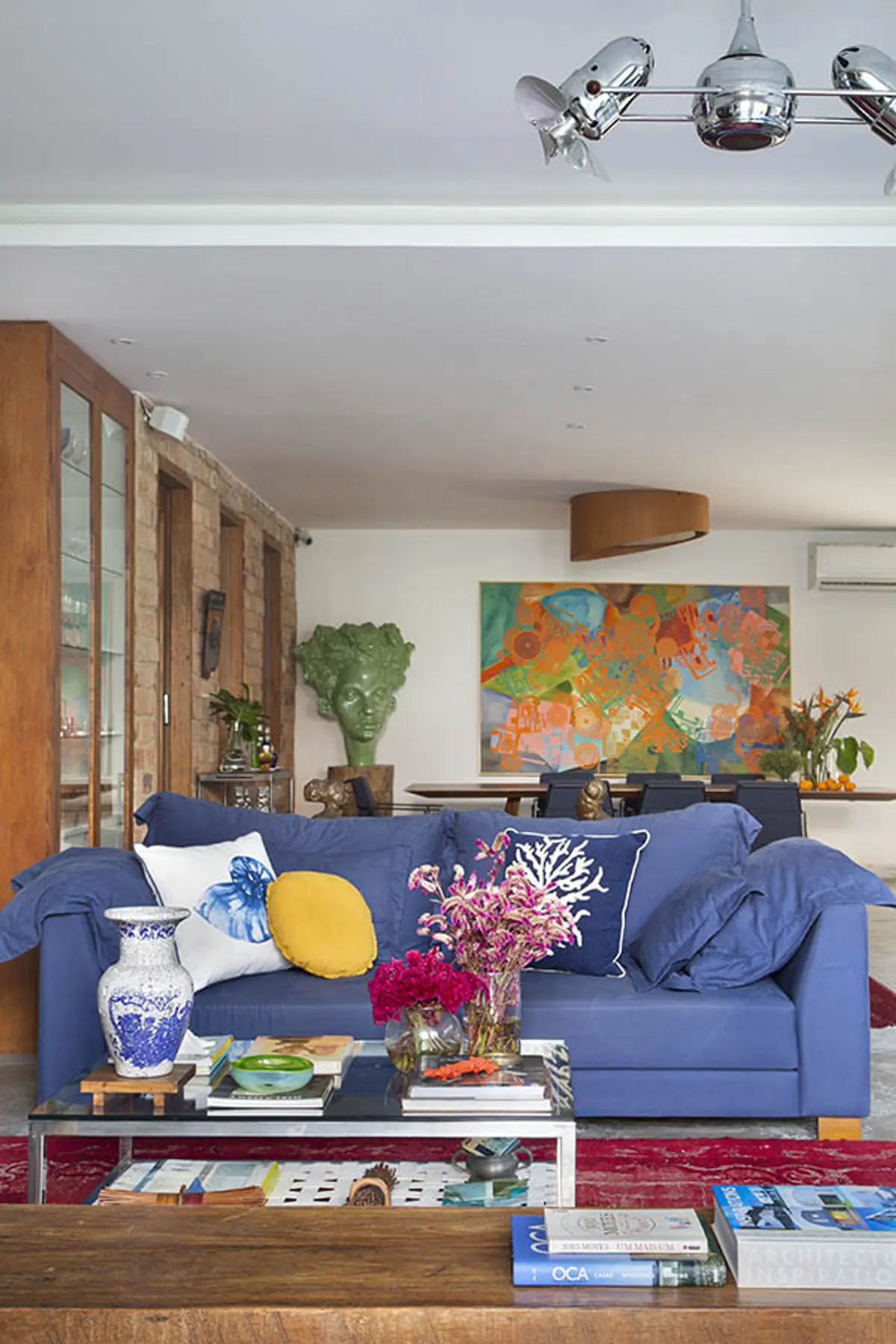 Living contemporaneo con sofa azul, muebles de madera y arte colorido — proyecto Casa Jardim Guanabara, por Amanda Miranda