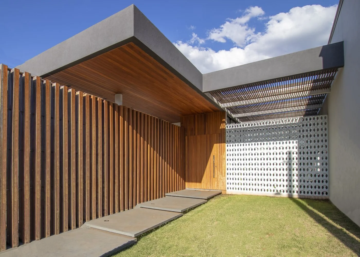Patio moderno con celosía de madera, pergola y cesped natural