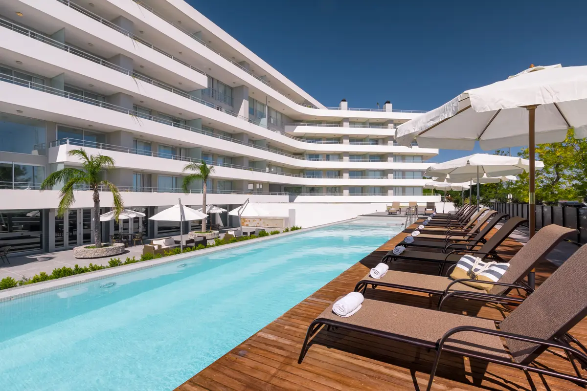 Edifício hoteleiro moderno com piscina e deck de madeira à beira-mar — projeto Dos Orillas, por Vanguarda Arquitectos, em Colonia del Sacramento Departamento de C