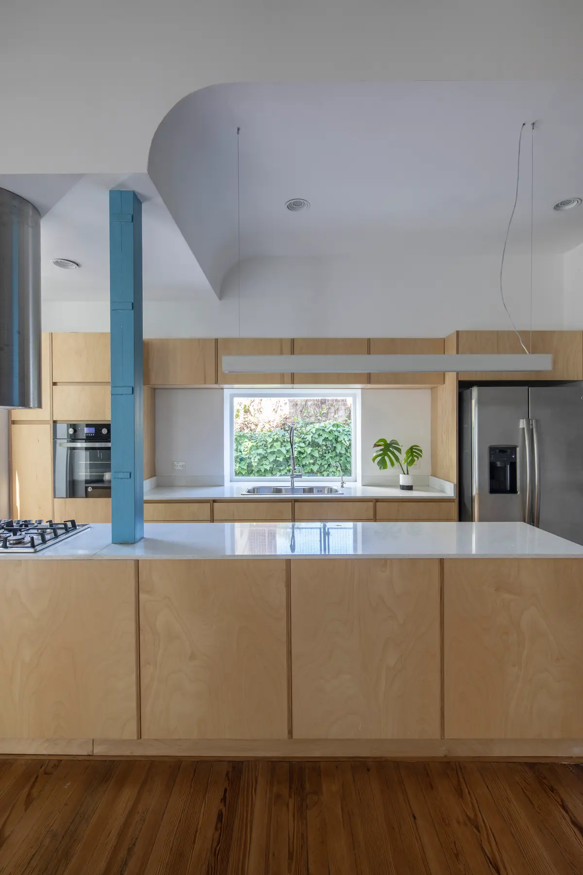 Cozinha moderna com ilha central, coluna azul e teto curvo — projeto Reforma Alsina, por Estudio YME, em San Isidro
