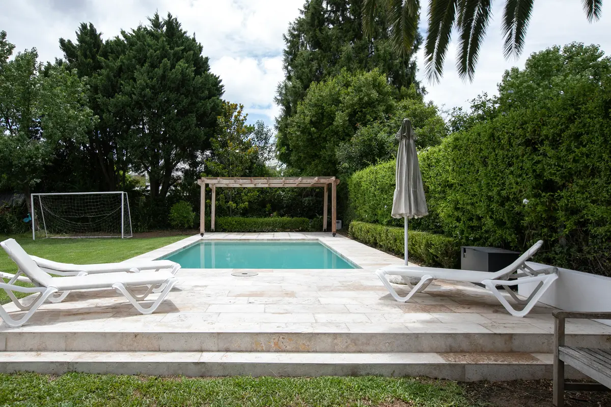 Piscina moderna rodeada de césped y pérgola — proyecto Obra La Posta, por Arq. Lourdes Yarade Saravia, en Pilar