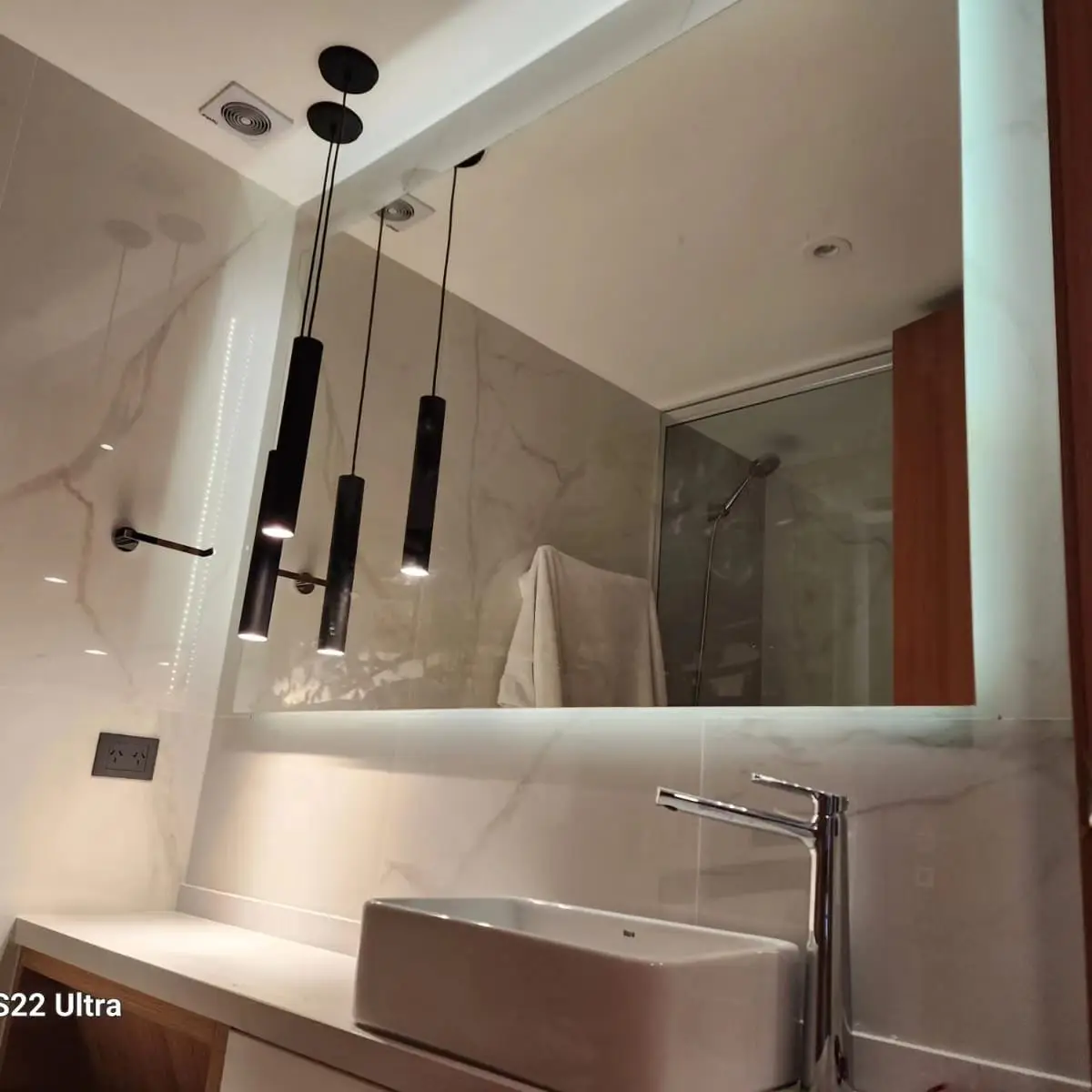 Baño moderno con paredes de mármol_like y luces colgantes negras — proyecto Espejo con bastidor y led, por Cristalcenter, en Recoleta