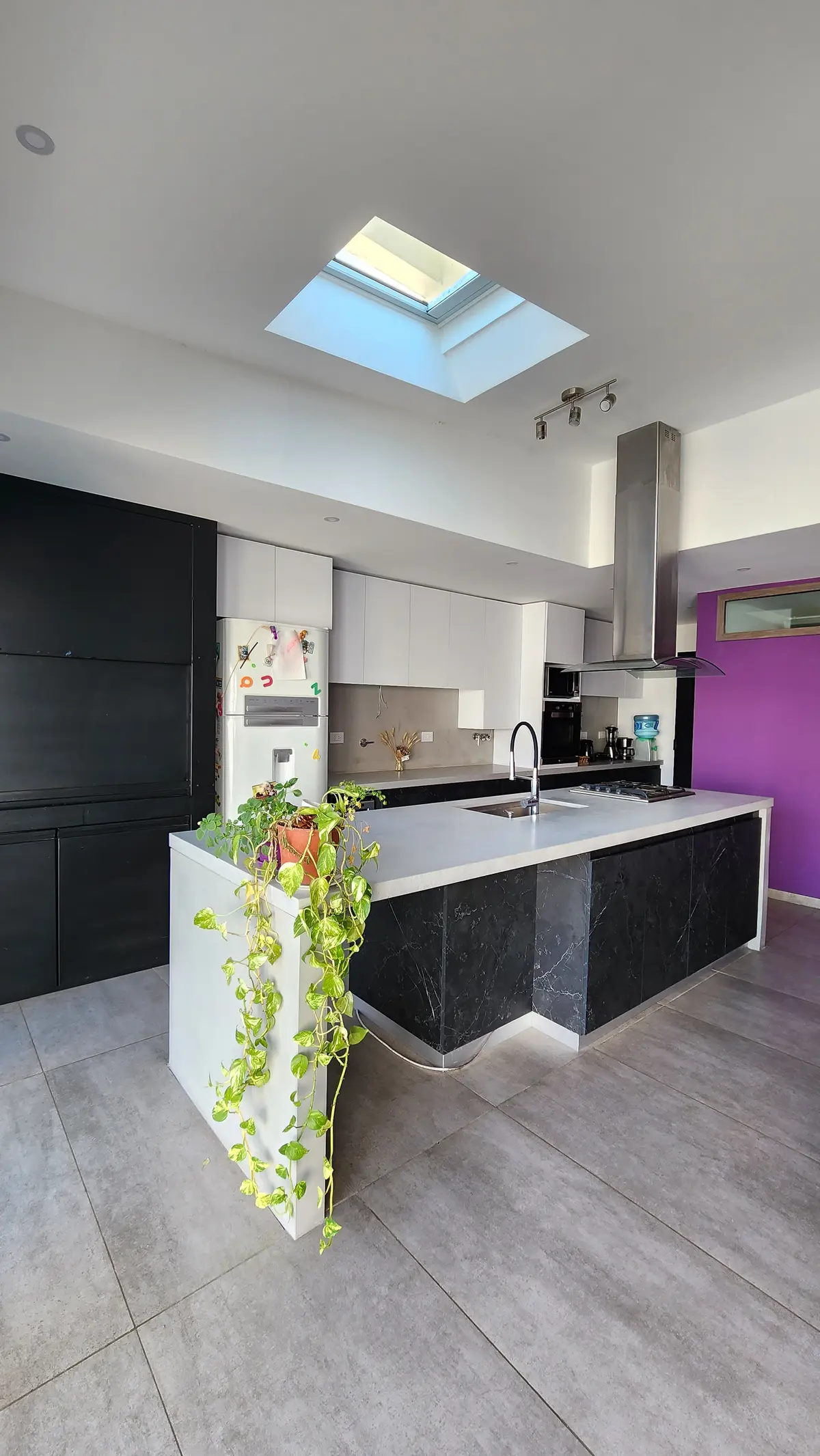 Cocina moderna con isla, luz cenital y pared violeta — proyecto Casa Berner, por Zima Arquitectura, en La Plata