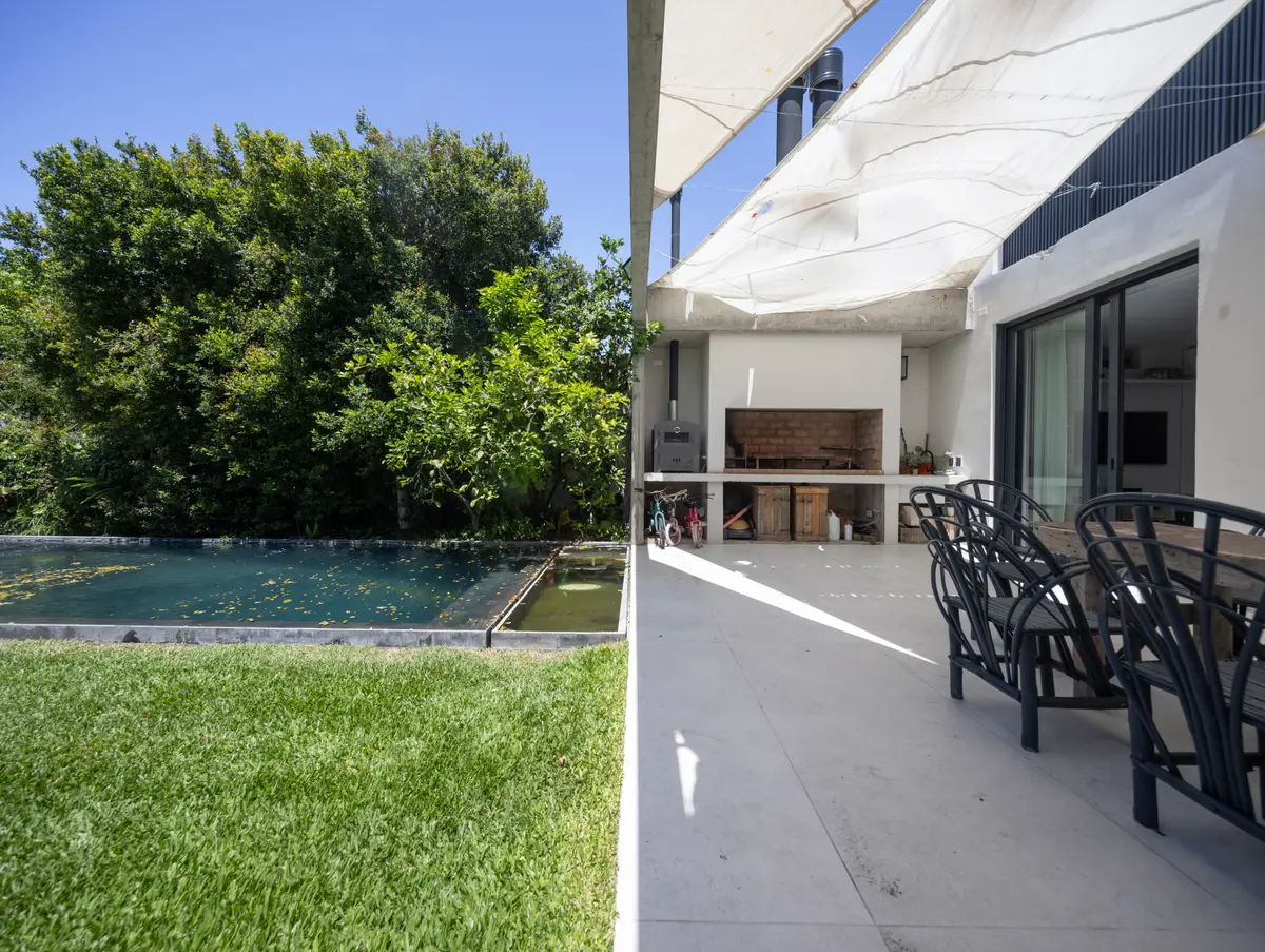 Pileta y parrilla moderna rodeada de verde — proyecto CASA OrBa, por Alfredo Orfila arquitectura, en San Isidro