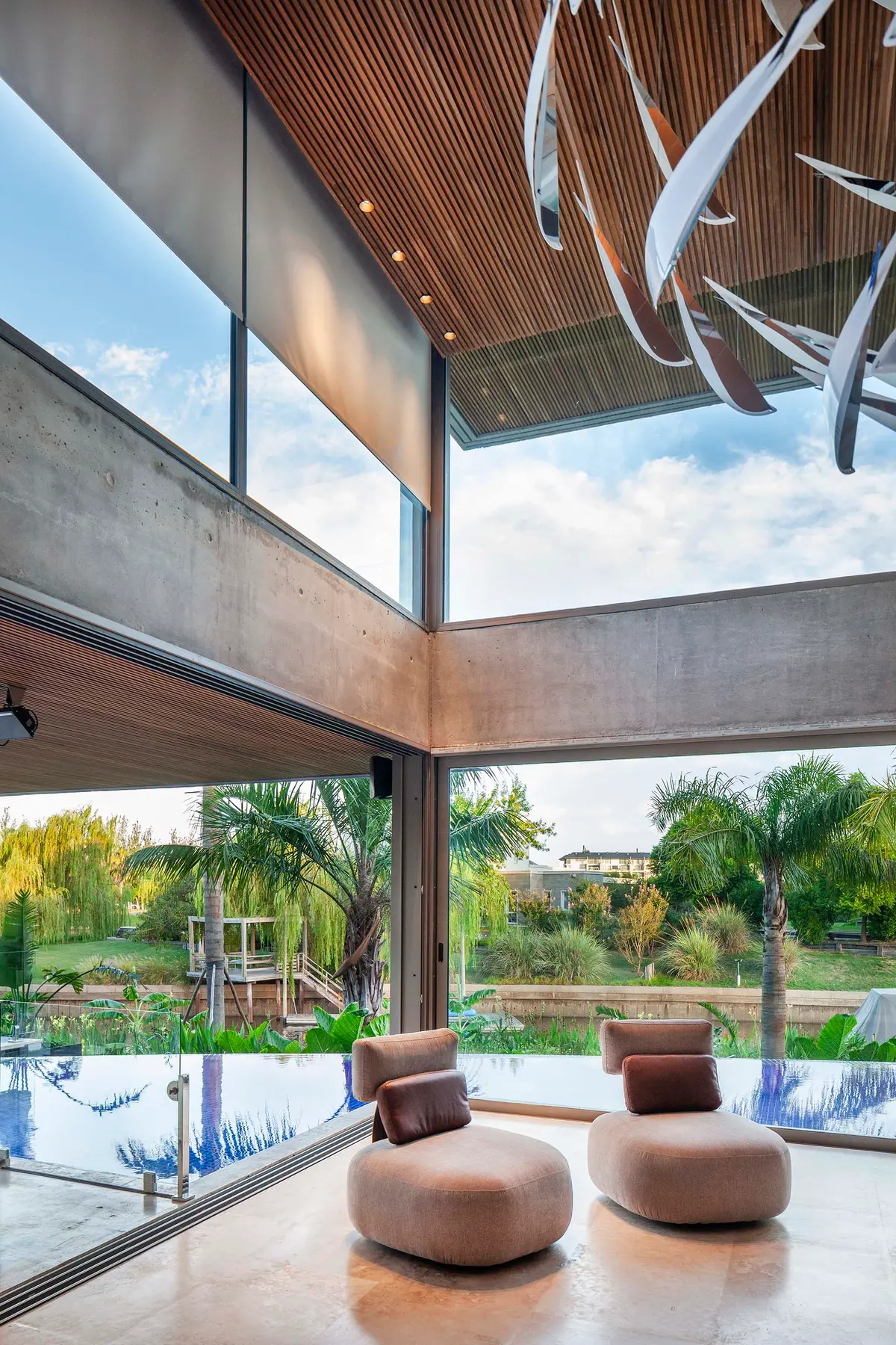 Sala de estar moderna com piscina e detalhes em madeira — projeto Water House, por Remy Arquitectos, em Rincón de Milberg