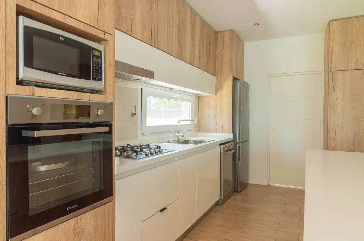 Cozinha moderna com armários de madeira natural e eletrodomésticos embutidos — projeto Reforma cocina, por Metro creativo, em Belén de Escobar