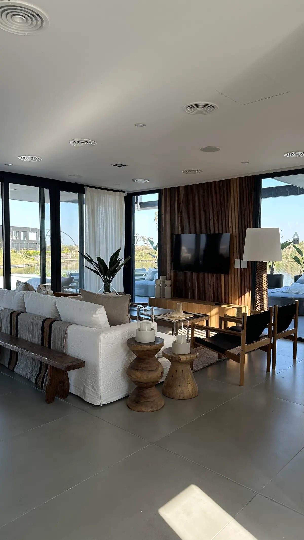 Sala de estar moderna com janelas do chão ao teto e parede de madeira — projeto Showroom Casa Mies, por Alejandra Nusenovich, em Belén de Escobar