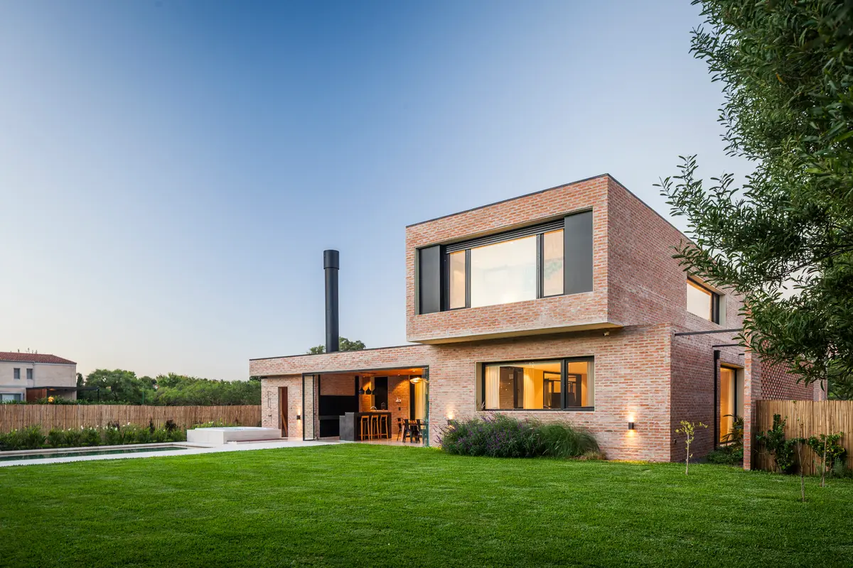 Fachada de casa moderna con ladrillos y grandes ventanales — proyecto Casa Brick, por LSA. , en Pilar