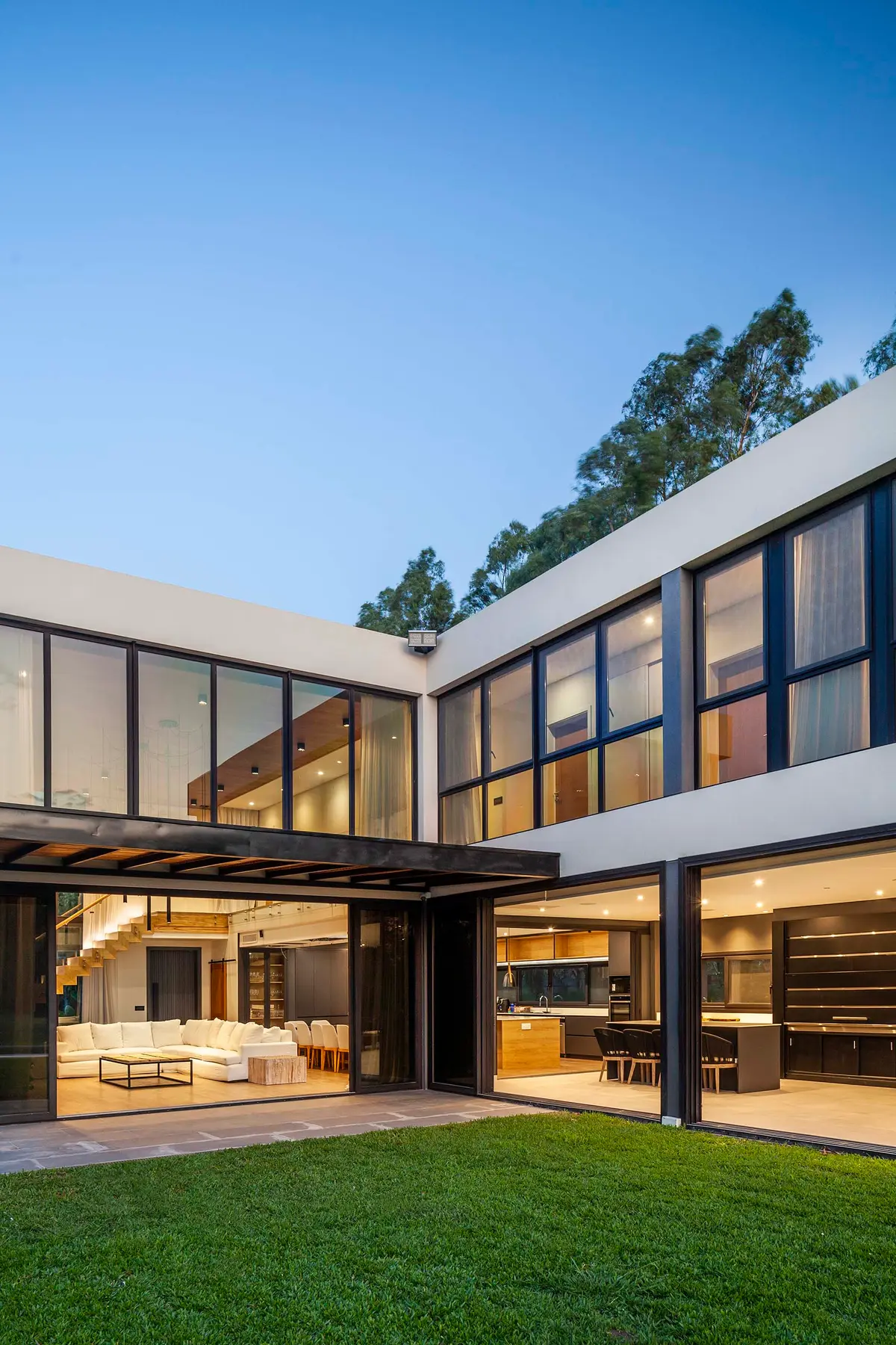 Fachada moderna com amplas janelas e sala de estar integrada ao exterior — projeto CASA T199, por A'PRIMA - Arquitectura Sustentable, em Los Robles 5901