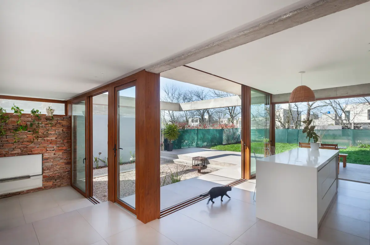 Cozinha moderna com ilha, tijolo aparente e vista para o jardim — projeto CASA CV, por BUSCETTI & DI BERNARDO arquitectas, em Gonnet