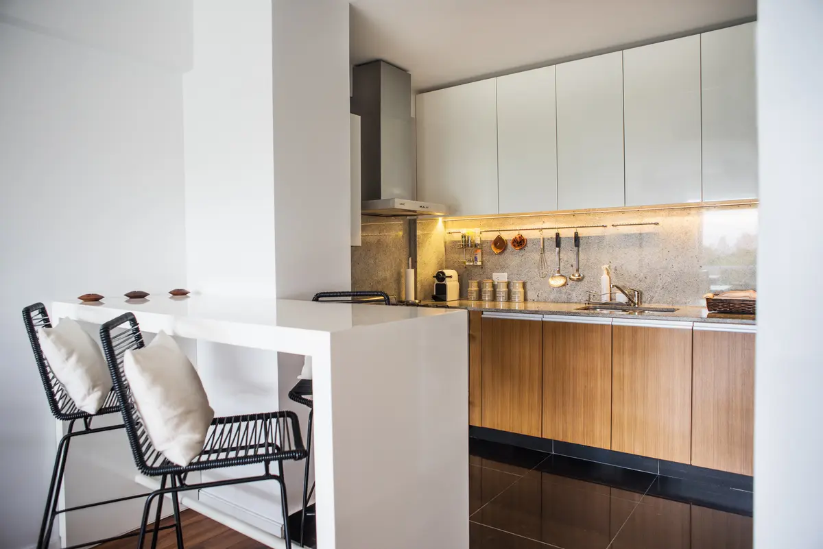 Cocina moderna con barra, muebles de madera y detalles en mármol — proyecto La Pampa, por Estudio Basa, en CABA