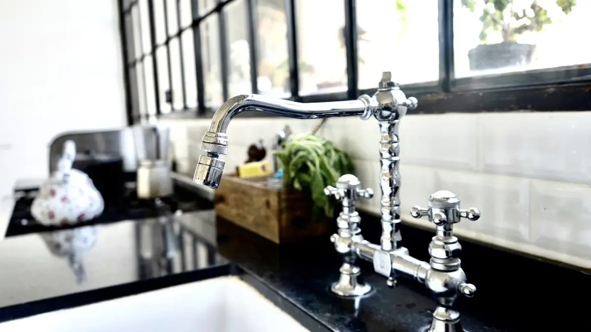 detalhe de torneira de cozinha com janela e objetos decorativos — projeto Los Jazmines Pilar del Este, por Marconi Silva Arquitectos, em Pilar del Este