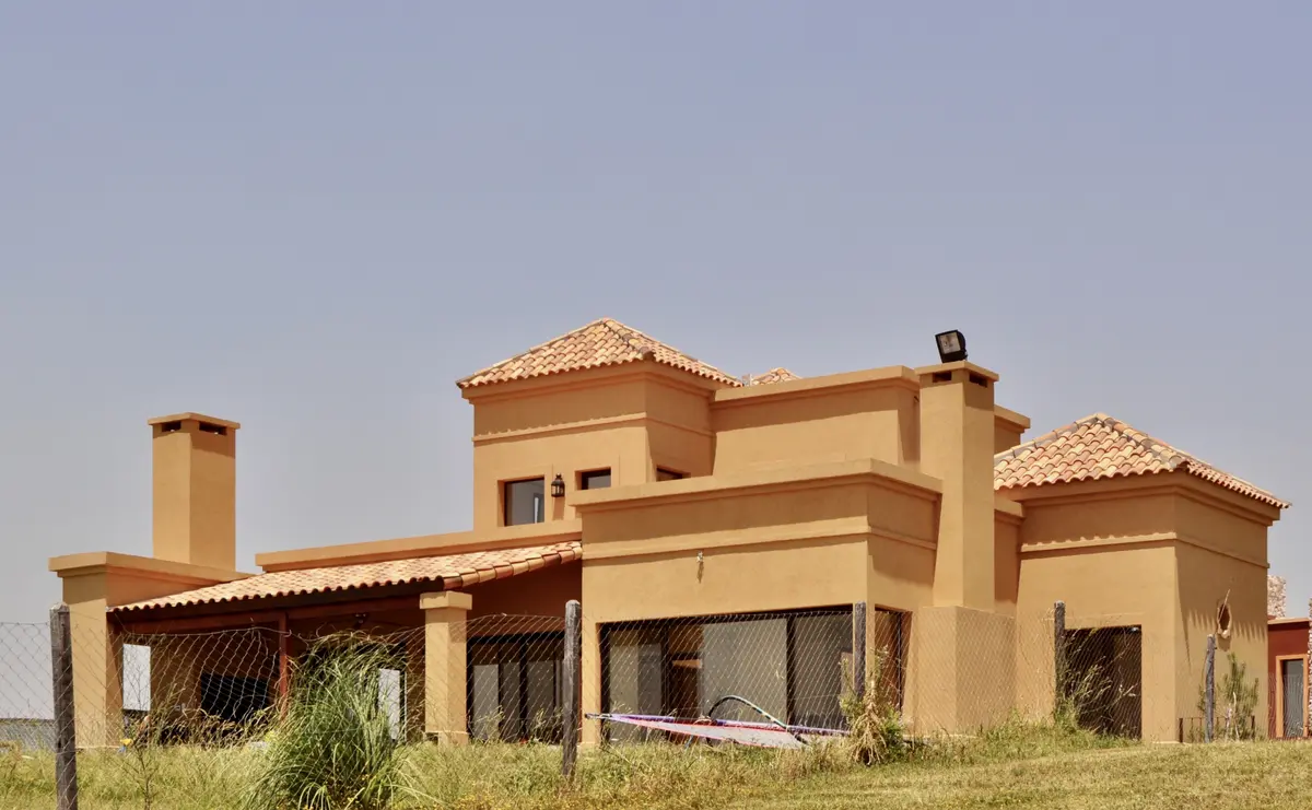 Casa de campo terracota com telhado de telhas e galeria externa — projeto San Marcos, por Marconi Silva Arquitectos, em Benavidez