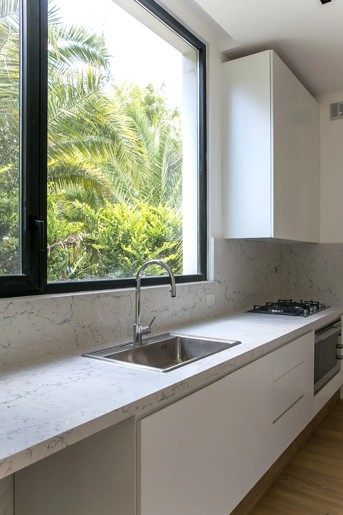 Cocina moderna con mesada de mármol y ventanal verde — proyecto Bosque Chico, por Estudio Arq. María Sioli, en Garin