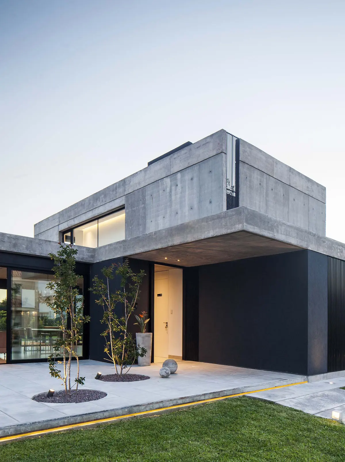Fachada moderna com concreto aparente, detalhes pretos e jardim exterior — projeto CASA EH, por GMARQ