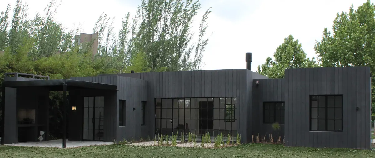 Fachada moderna de casa com revestimento preto e churrasqueira externa — projeto Casa Recodo, por Ronda Arquitectura, em Garin