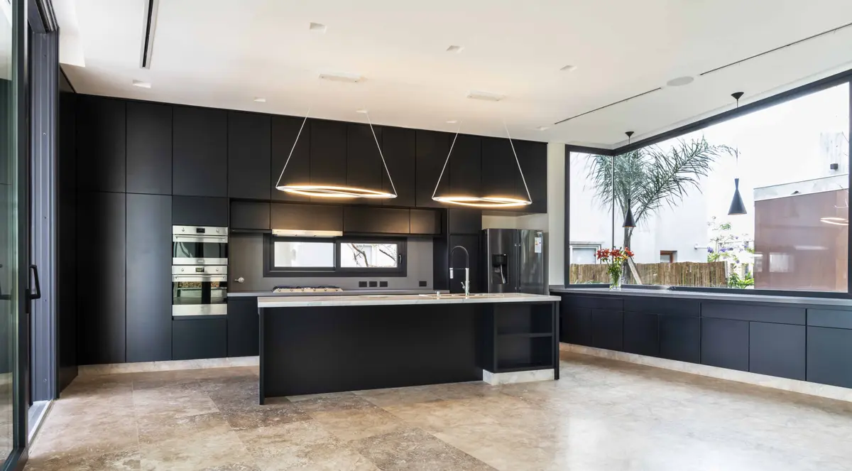 Cocina moderna negra minimalista con isla grande y ventanas al exterior — proyecto Casa CZ, por Estudio Juan Trivelloni