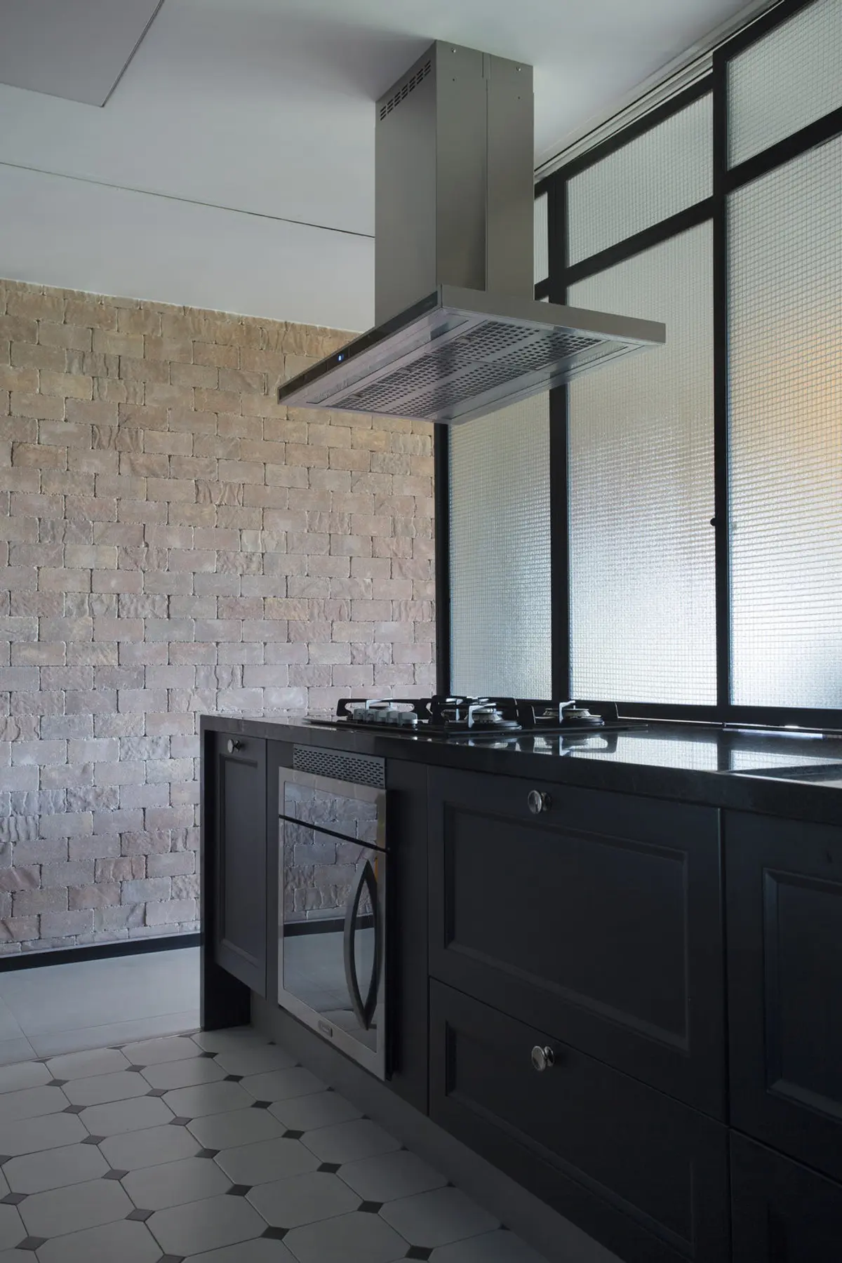 Cocina industrial con ladrillo visto, isla negra y campana acero — proyecto BL House, por Studio Ro-ca
