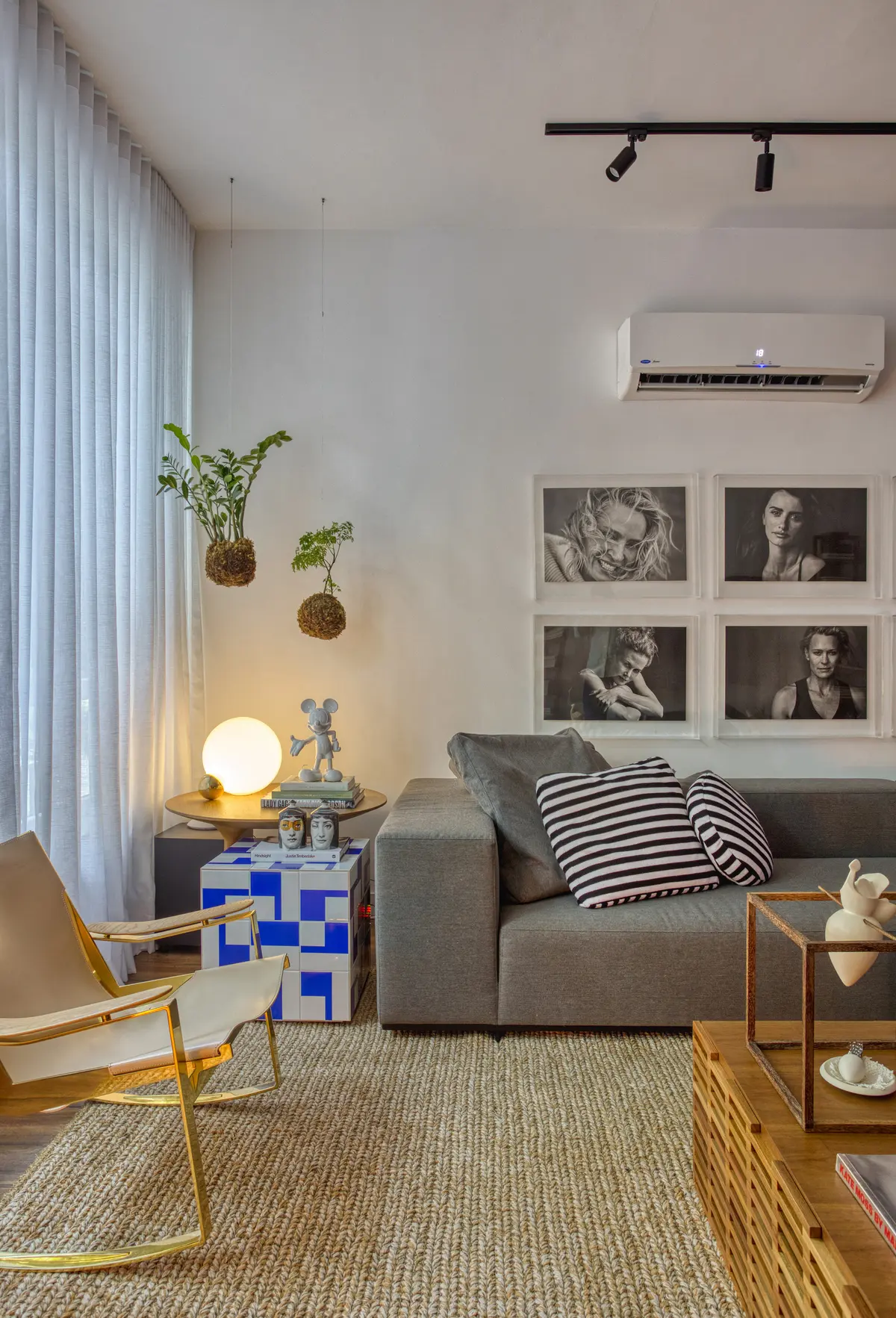 Living minimalista con sofa gris, plantas colgantes y arte en pared — proyecto Hugo Gloss, por Studio Ro-ca