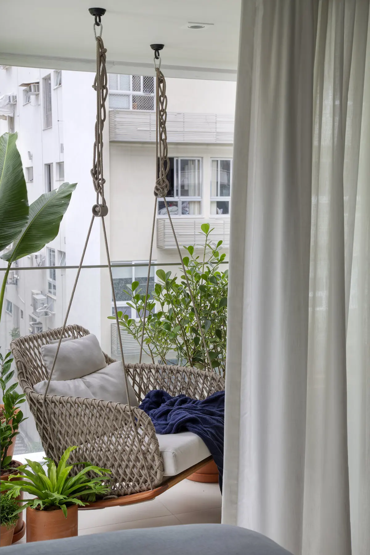 Balcón con sillón colgante tejido y plantas en maceta — proyecto JG House, por Studio Ro-ca