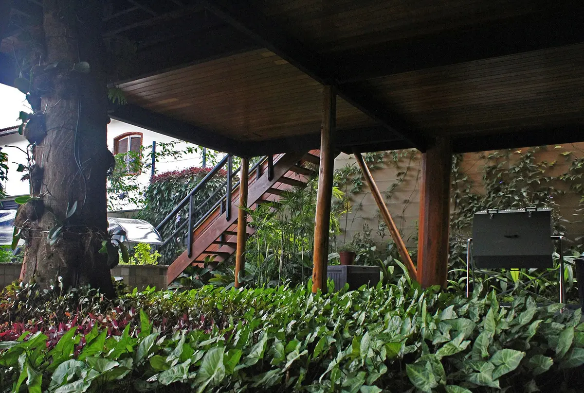 Patio cubierto con pergola de madera bajo árbol grande con plantas — proyecto Residência JB, por Gil Fialho