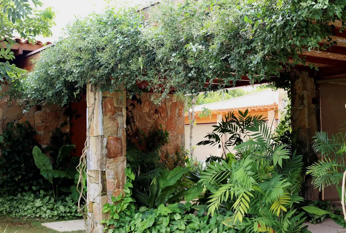 Patio rustico con pergola, plantas colgantes y muros envejecidos — proyecto Residência VL, por Gil Fialho