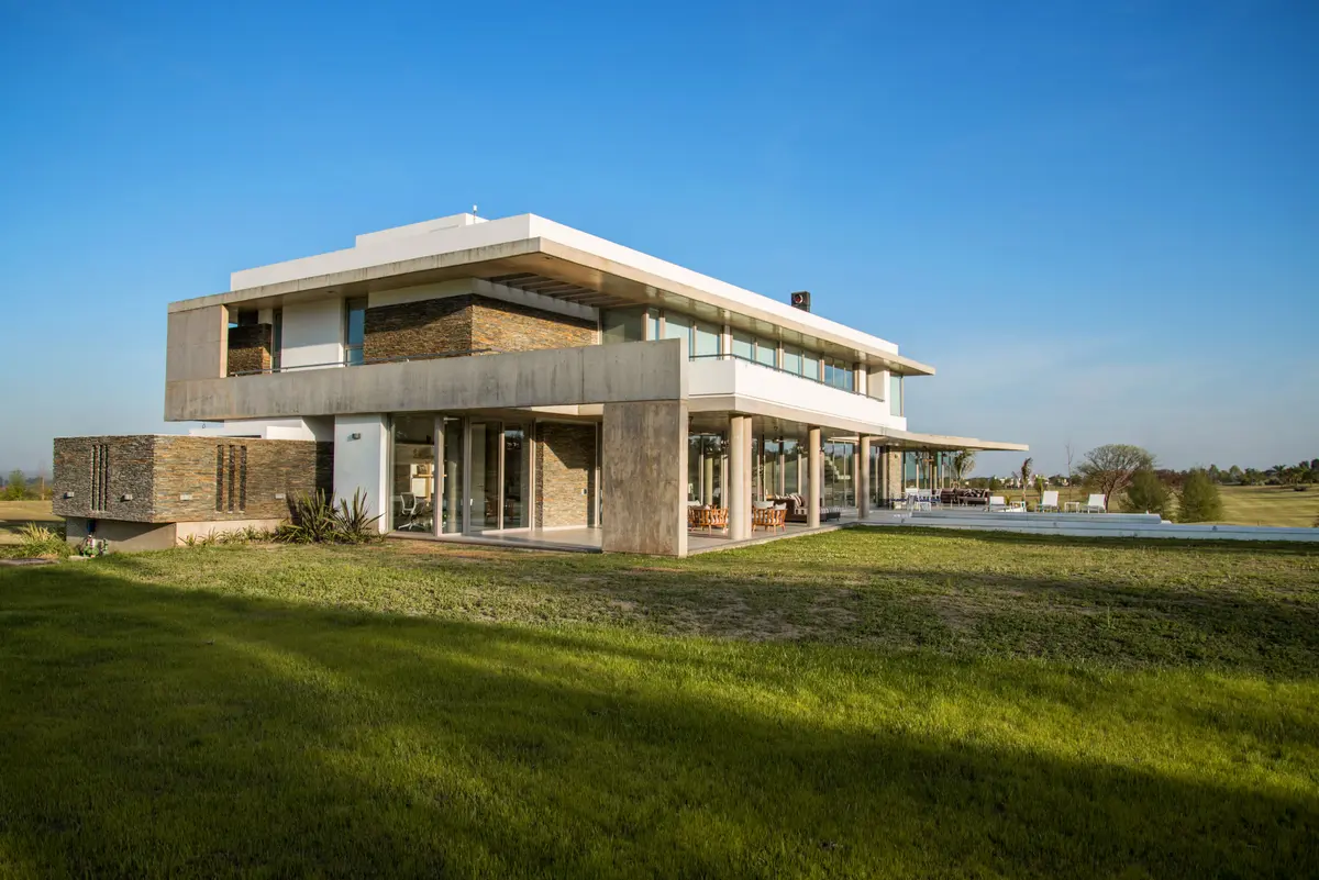 casa moderna com janelas grandes e gramado — projeto MM / Vivienda, por Saez Sanchez Arquitectos, em San Pablo Country Life & Golf