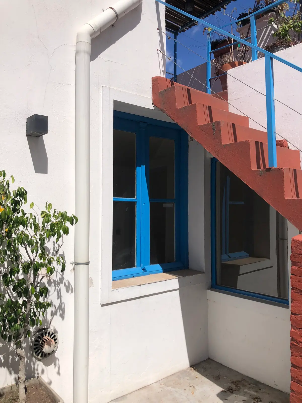 Escada flutuante vermelha com corrimão azul em frente a fachada branca — projeto Abel & Gaby, por Costantini studio, em Buenos Aires