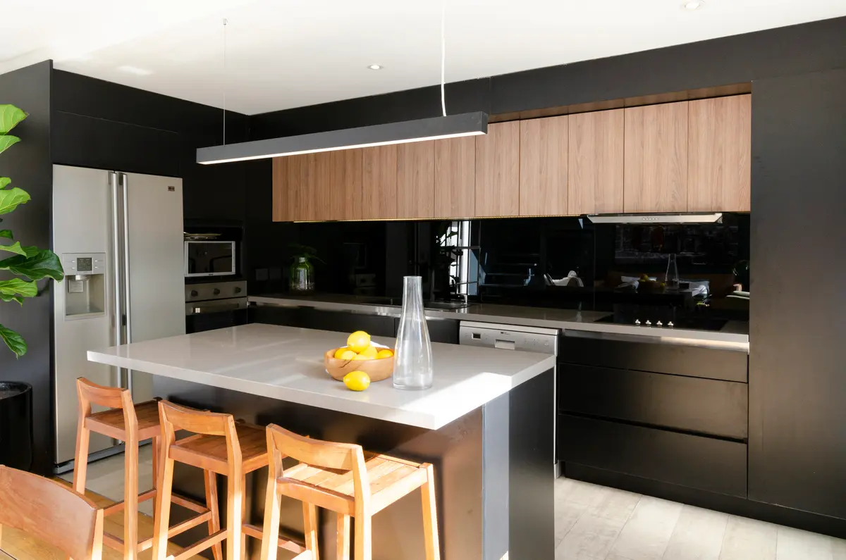 Cocina moderna con isla, madera natural y paredes oscuras — proyecto Guayra - Andrea Gonzales, por ABEJA CONCEPT, en Belgrano