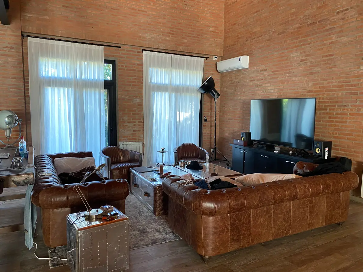 Sala de estar com tijolos aparentes e sofás de couro — projeto Loft y garage autos de colección, por Arq. Damian Fainzilber, em San Isidro