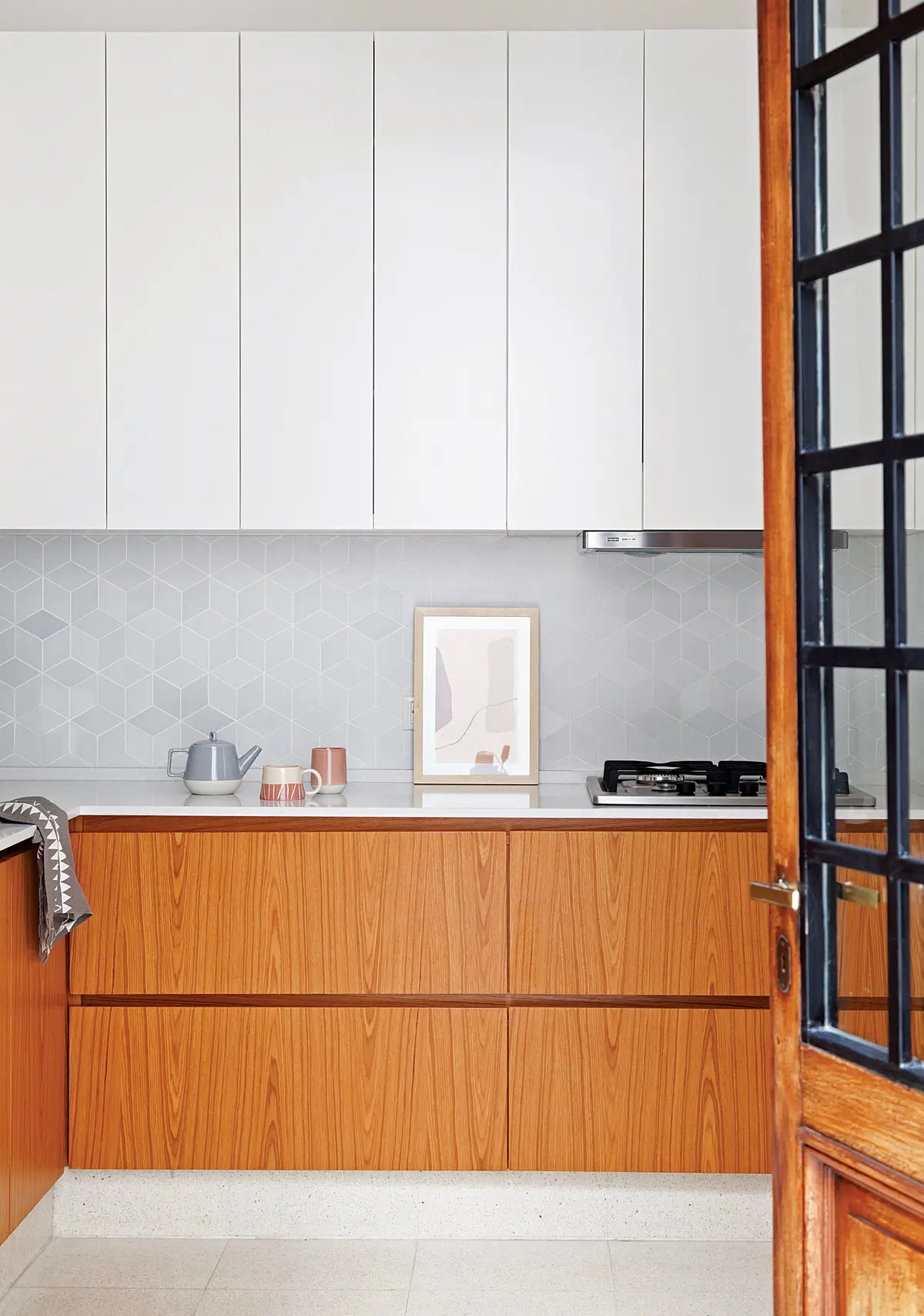 Cocina moderna minimalista con gabinetes de madera y detalles geométricos — proyecto Obra HNDRS, por Ideï Arquitectura, en CABA