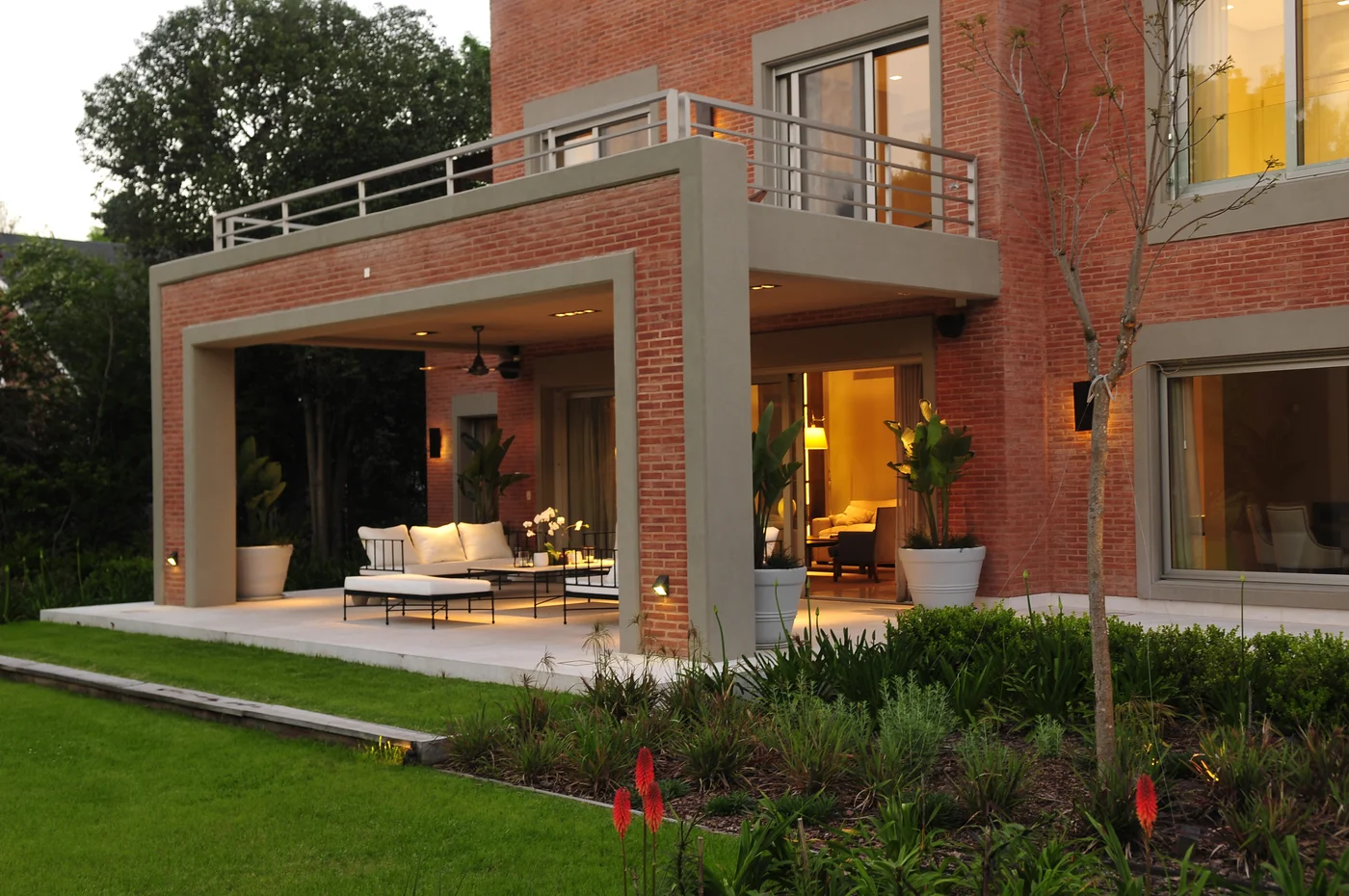 Patio moderno con ladrillo visto y grandes ventanales