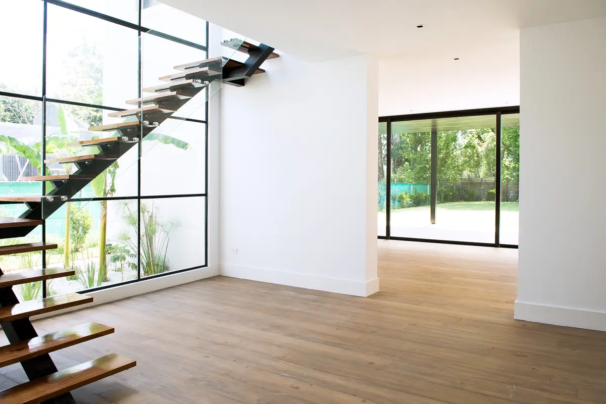 Interior moderno com escada flutuante e janelas do chão ao teto — projeto Bosque Chico, por Estudio Arq. María Sioli, em Garin
