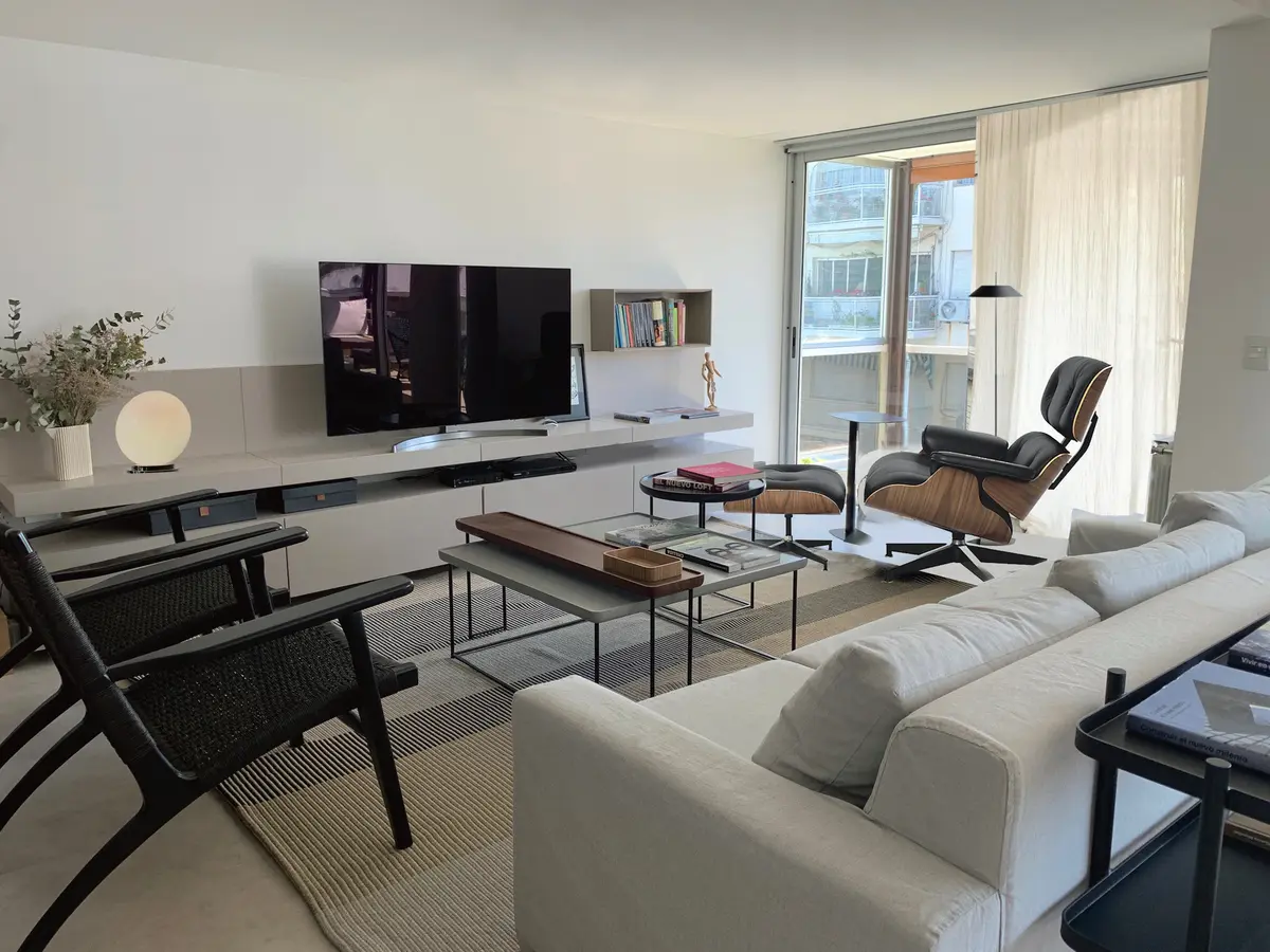 Sala moderna com poltrona icônica e muita luz natural — projeto Conde, por Bimba Estudio, em CABA