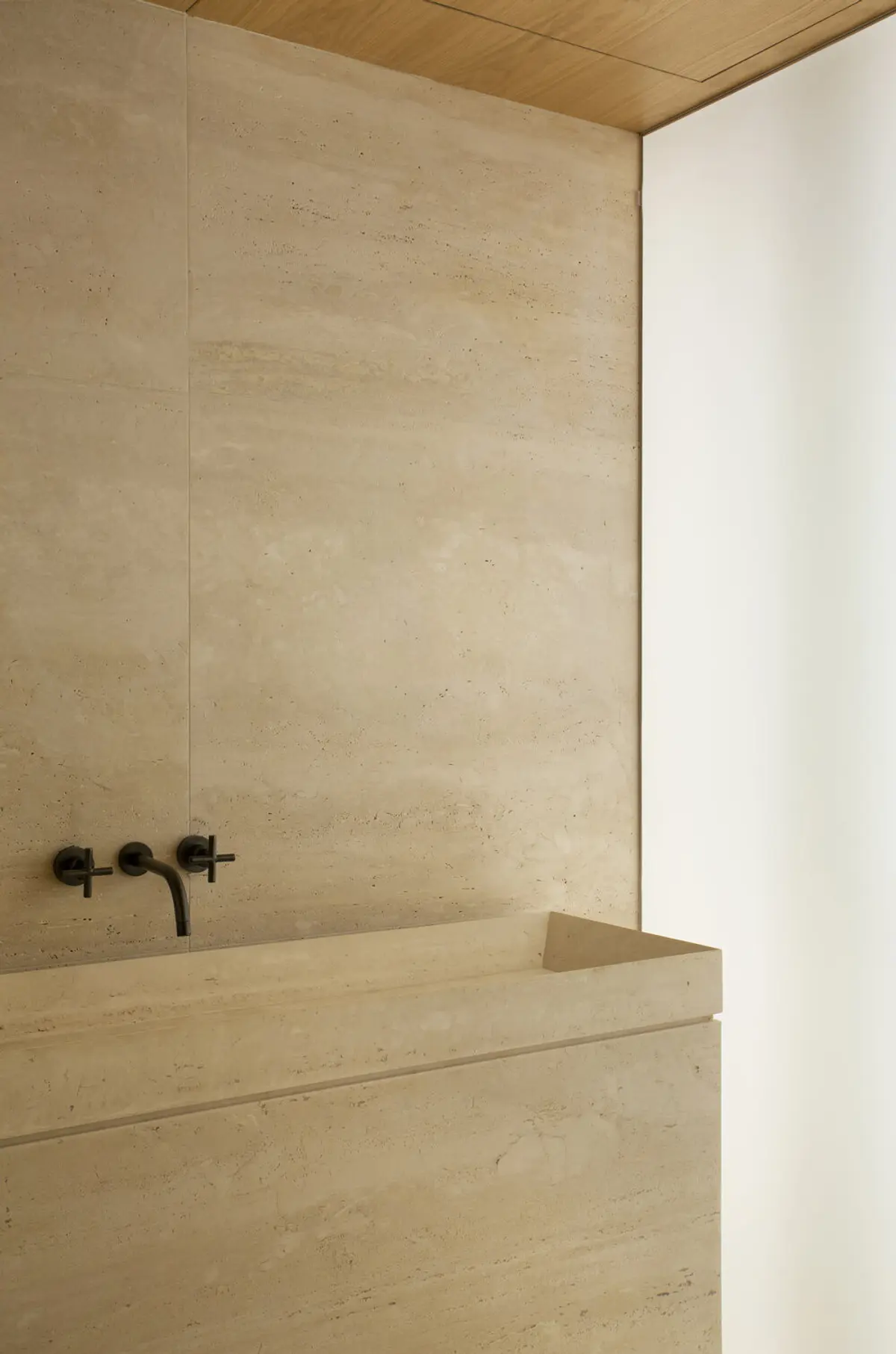 Baño minimalista con bañera de piedra y grifo negro empotrado — proyecto PS House, por Studio Ro-ca