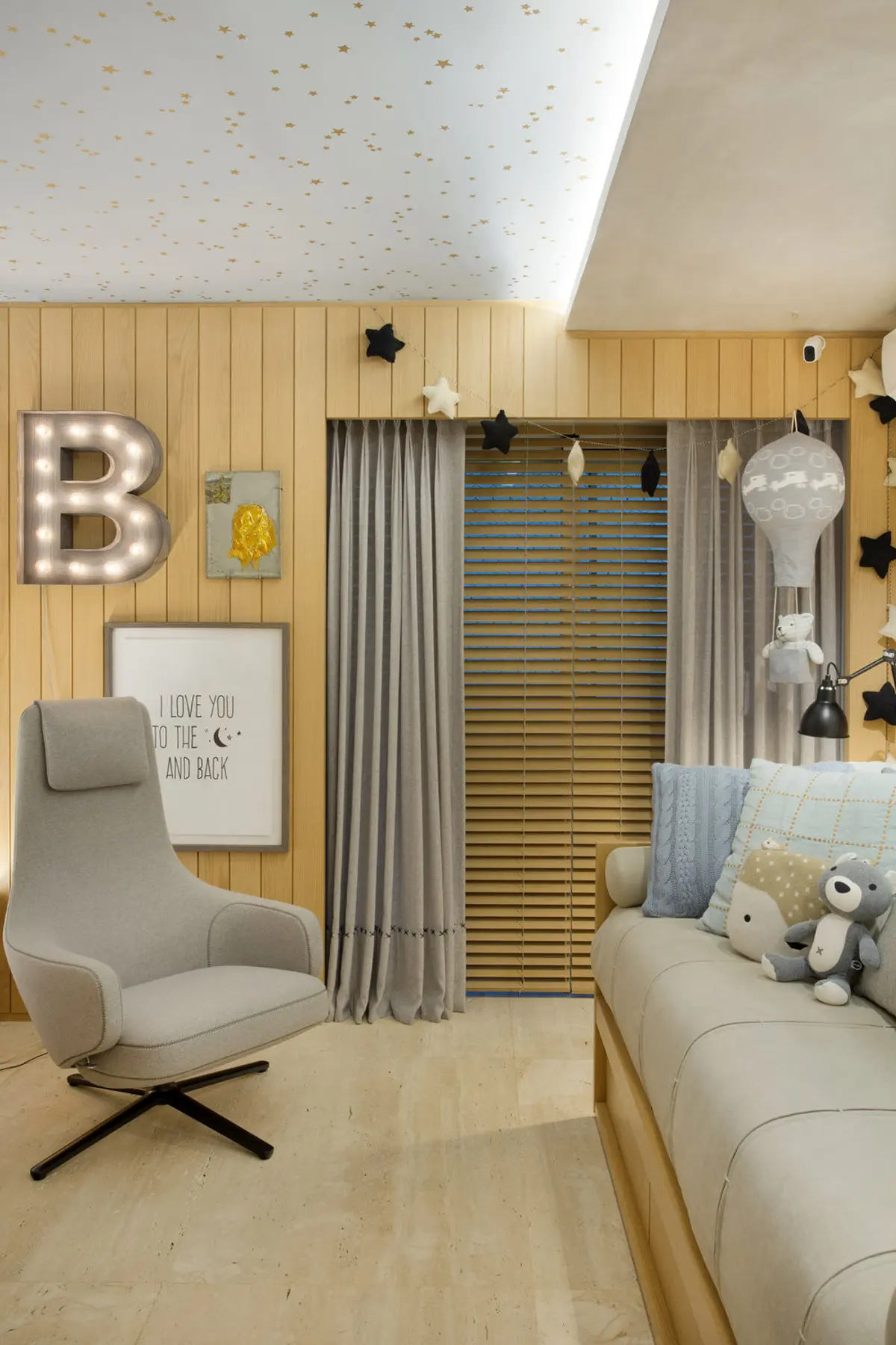 Dormitorio infantil con revestimiento madera, cama y sillón gris, letrero luminoso B — proyecto Quarto Bernardo, por Studio Ro-ca