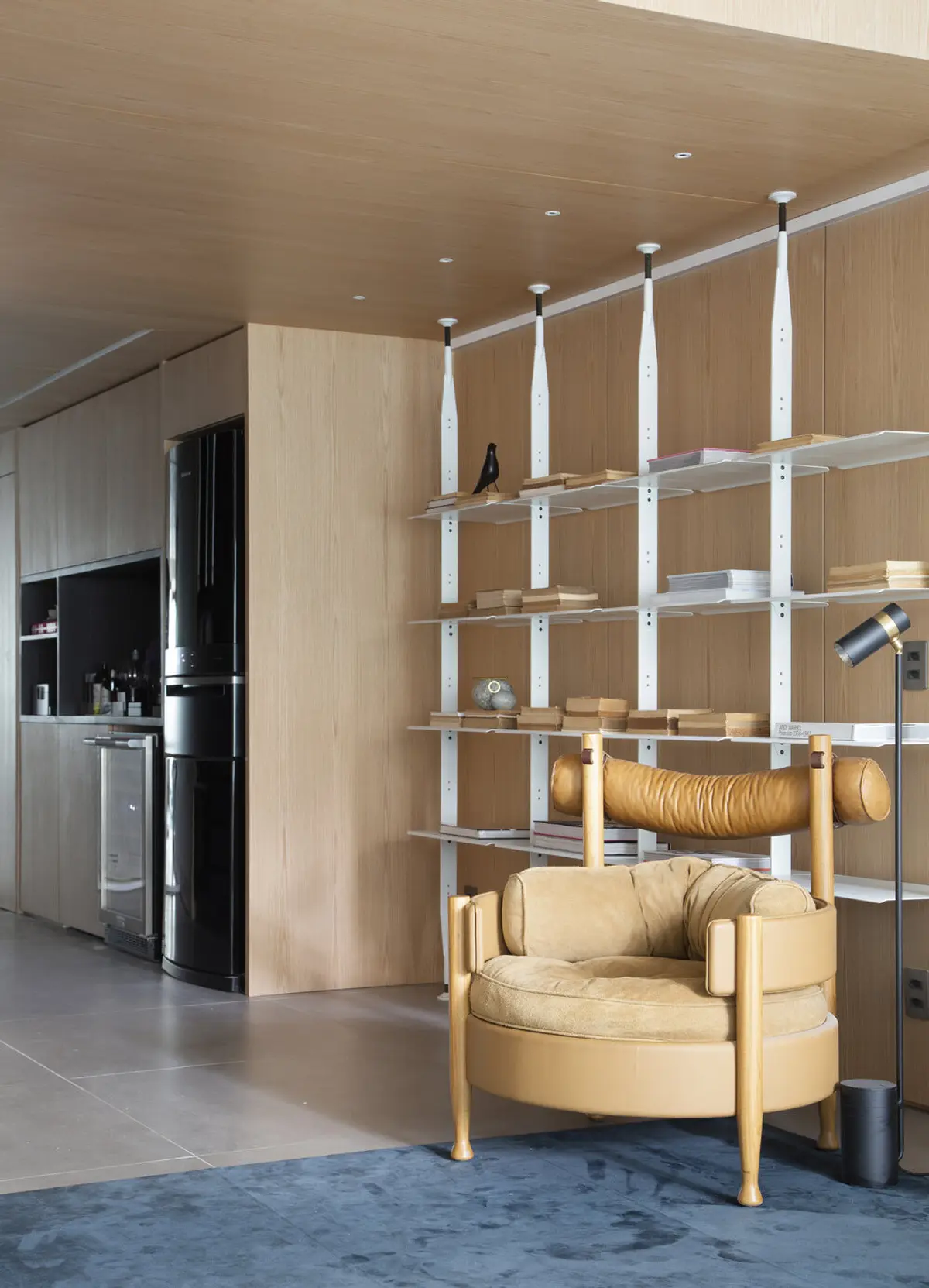 Living moderno con sillón beige, estantes blancos y pared de madera natural — proyecto MN House, por Studio Ro-ca
