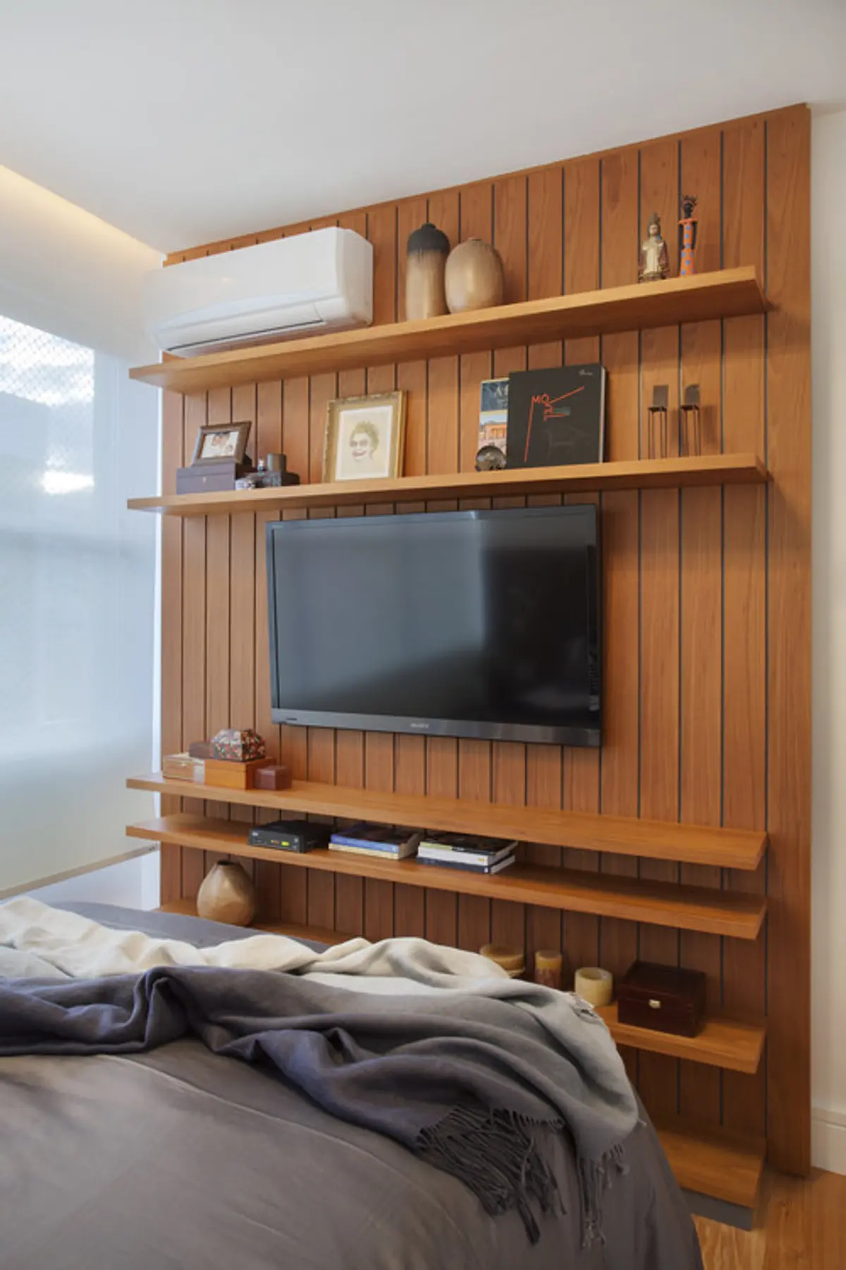 Dormitorio con pared de madera vertical, TV empotrada y estantes flotantes — proyecto MS House, por Studio Ro-ca