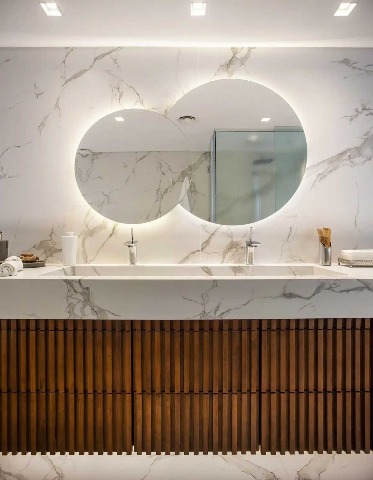 Baño moderno con doble vanitory y espejos ovalados retroiluminados — proyecto Pacífico BRT, por Vanguarda Arquitectos, en CABA