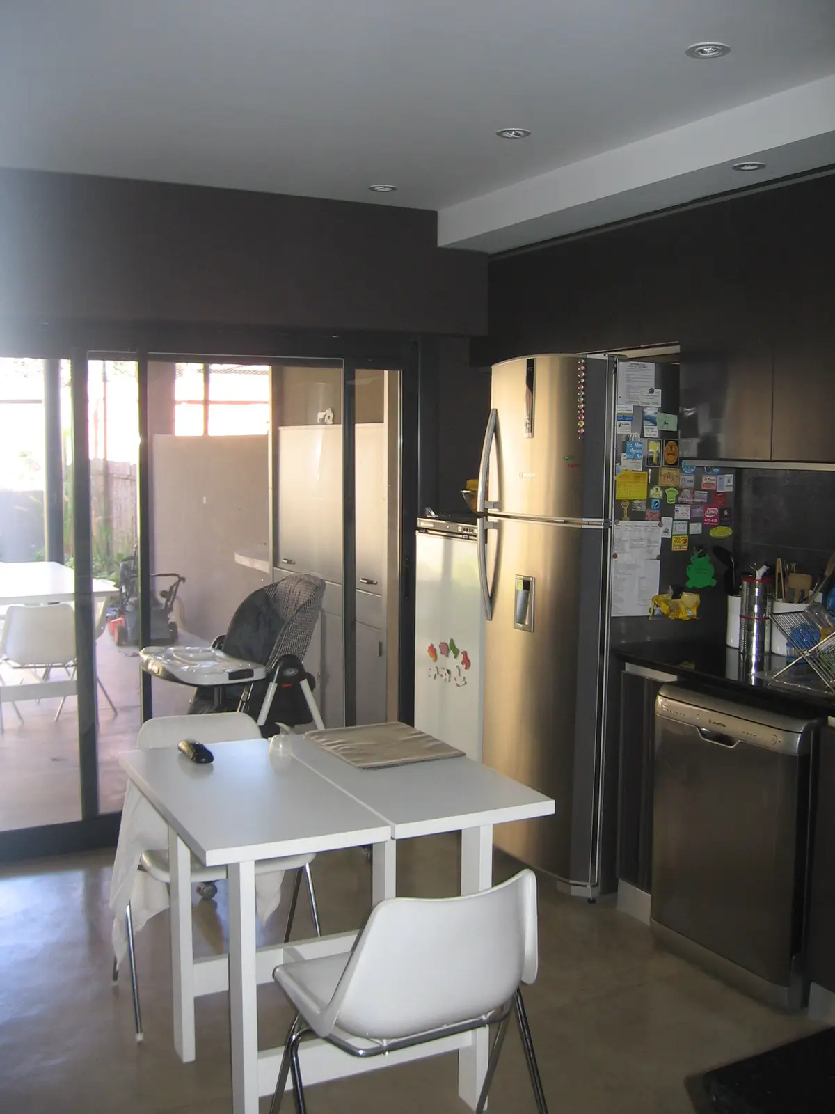 Cocina moderna minimalista con isla central blanca y acceso a patio — proyecto San Isidro, por Rioja Arquitectura, en San Isidro