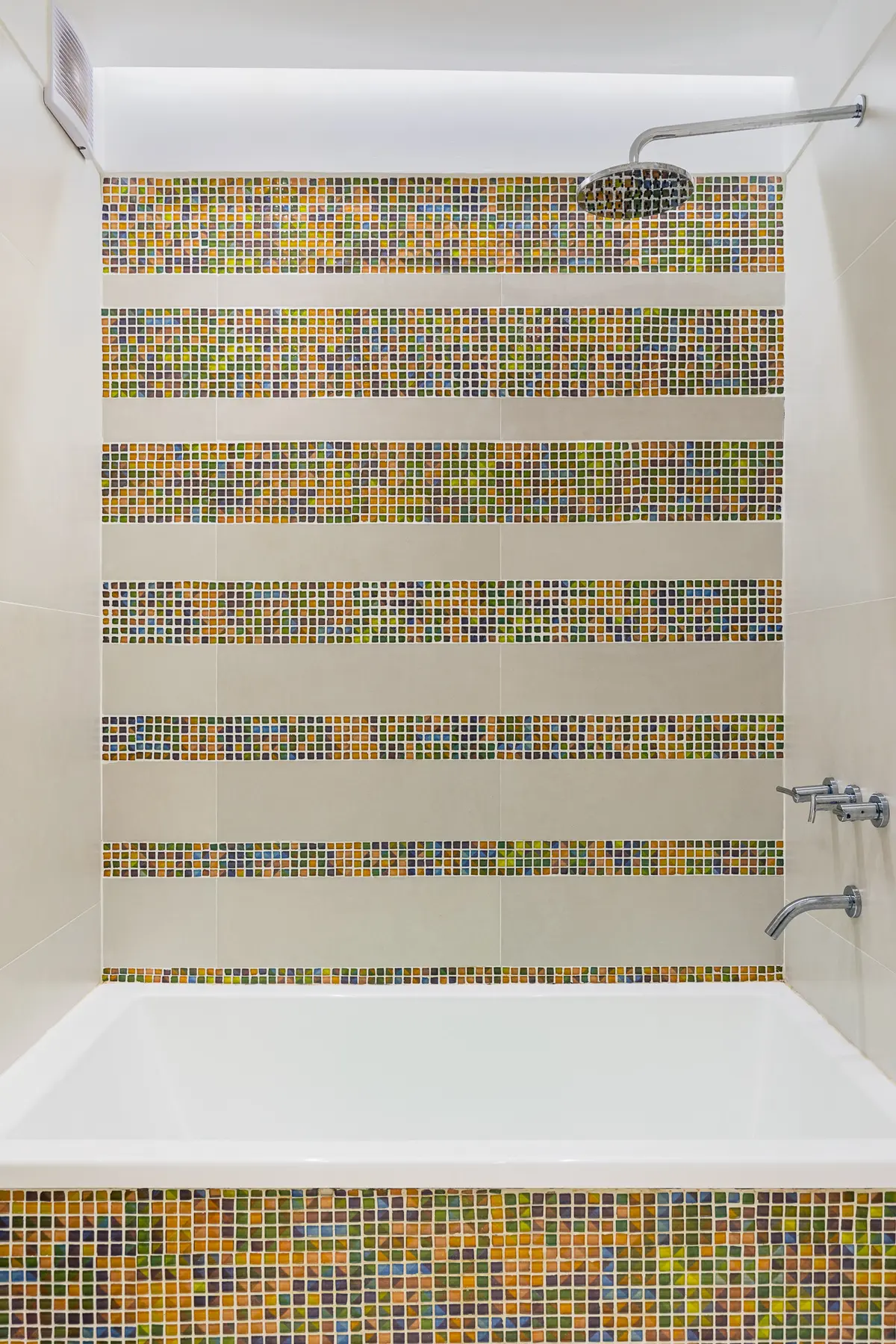 Banheiro moderno com banheira branca e paredes com faixas de mosaico — projeto Baño en Belgrano, por MARCO GUOLI PHOTO, em Belgrano