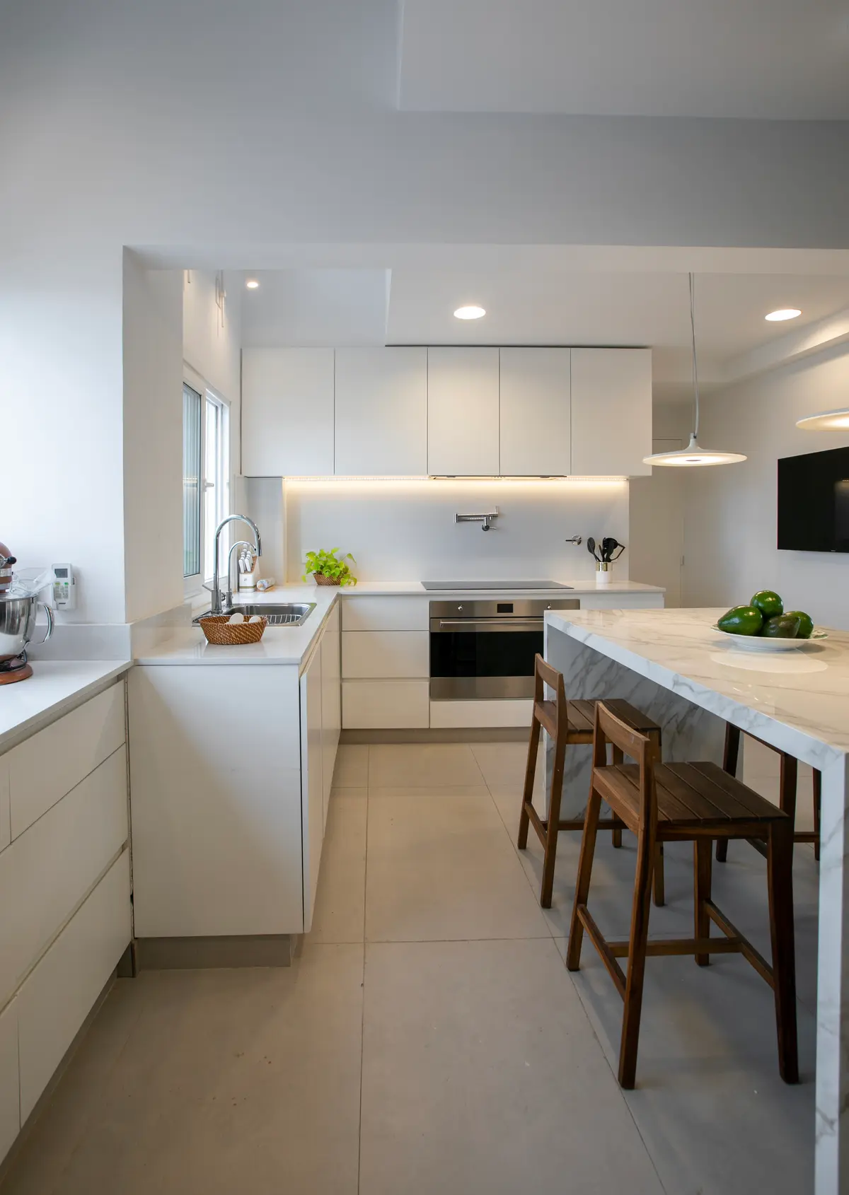 Cocina moderna blanca con isla de mármol y taburetes de madera — proyecto Obra Araoz A, por Arq. Lourdes Yarade Saravia, en Buenos Aires