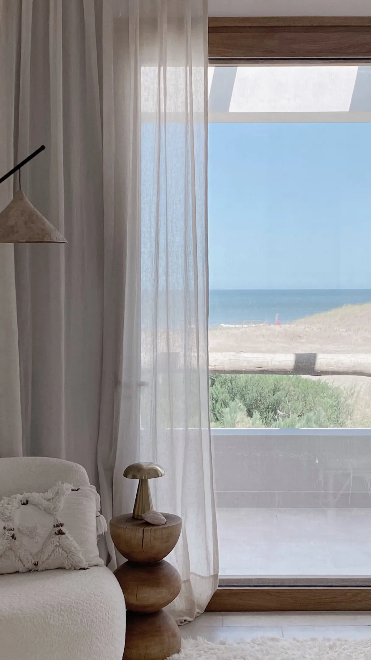 Living con vista al mar, cortinas de lino y sillón texturizado — proyecto El Refugio, por Grupo Pauta Arquitectura, en Pinamar