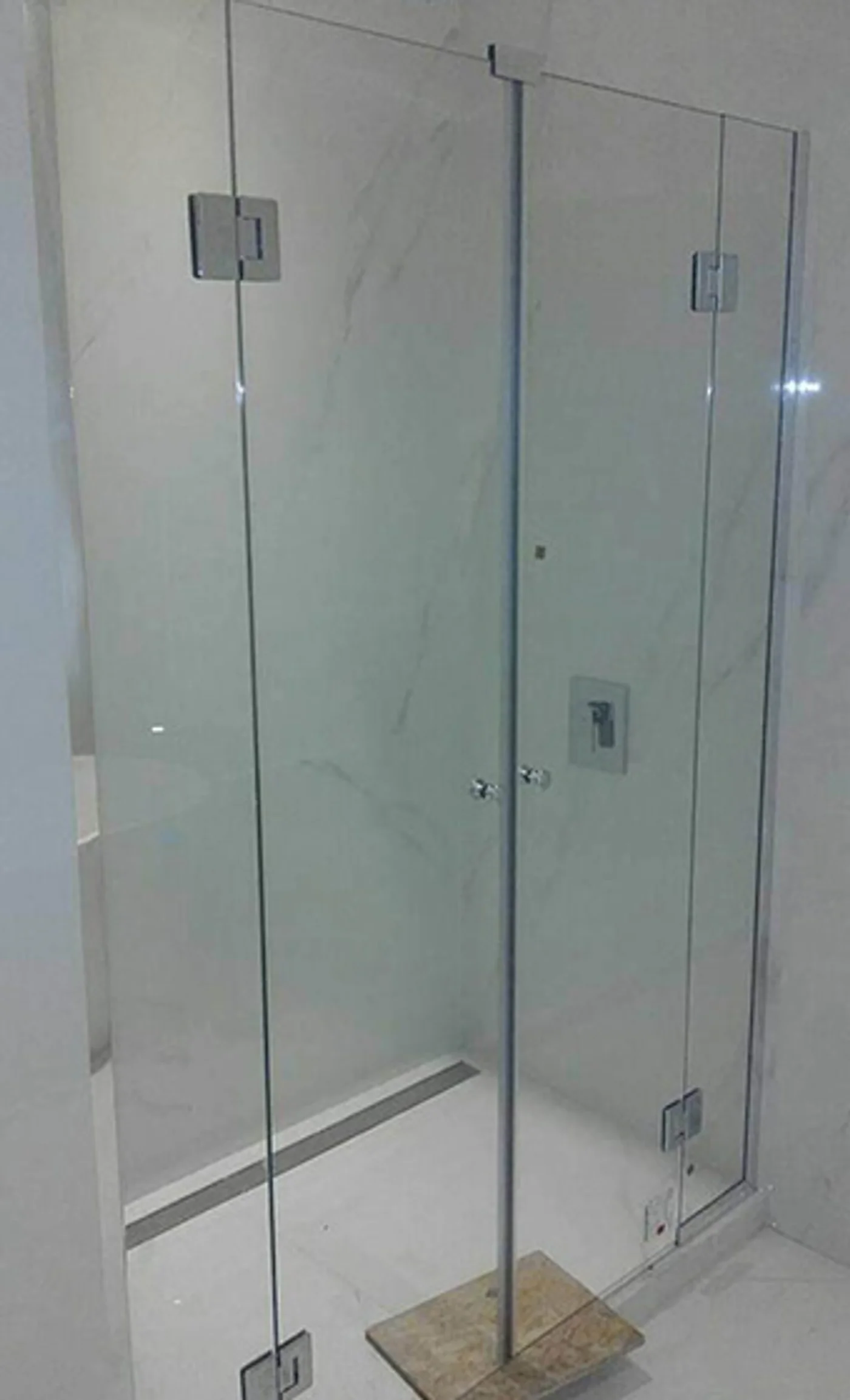 Baño moderno con mampara de vidrio sin marco y revestimiento de mármol