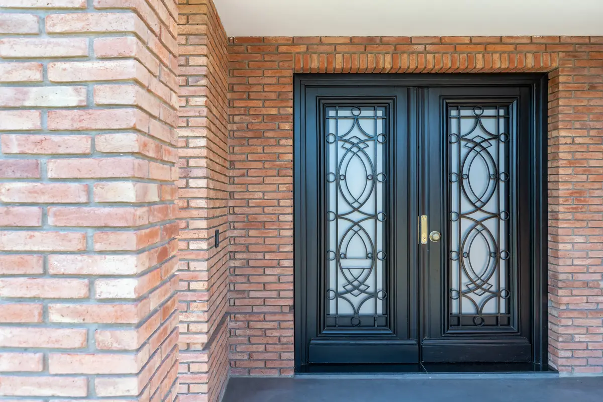 Puerta doble de metal negro con detalles de vidrio en fachada de ladrillo — proyecto VIVIENDA L.L, por Lorenabusquetsarquitectura, en Córdoba